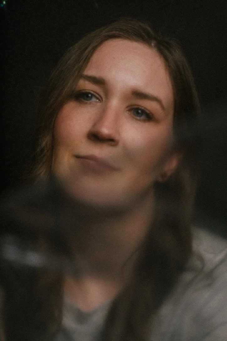 Person looking past camera, soft focus, black background.