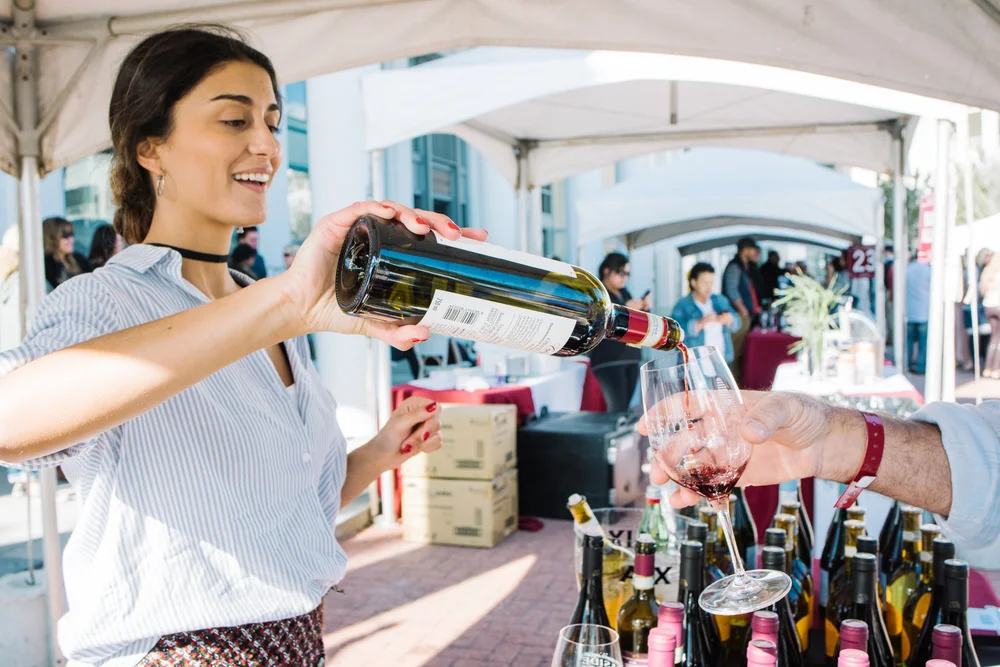 A woman pouring wine into a glass at the Seeing Red Wine Festival