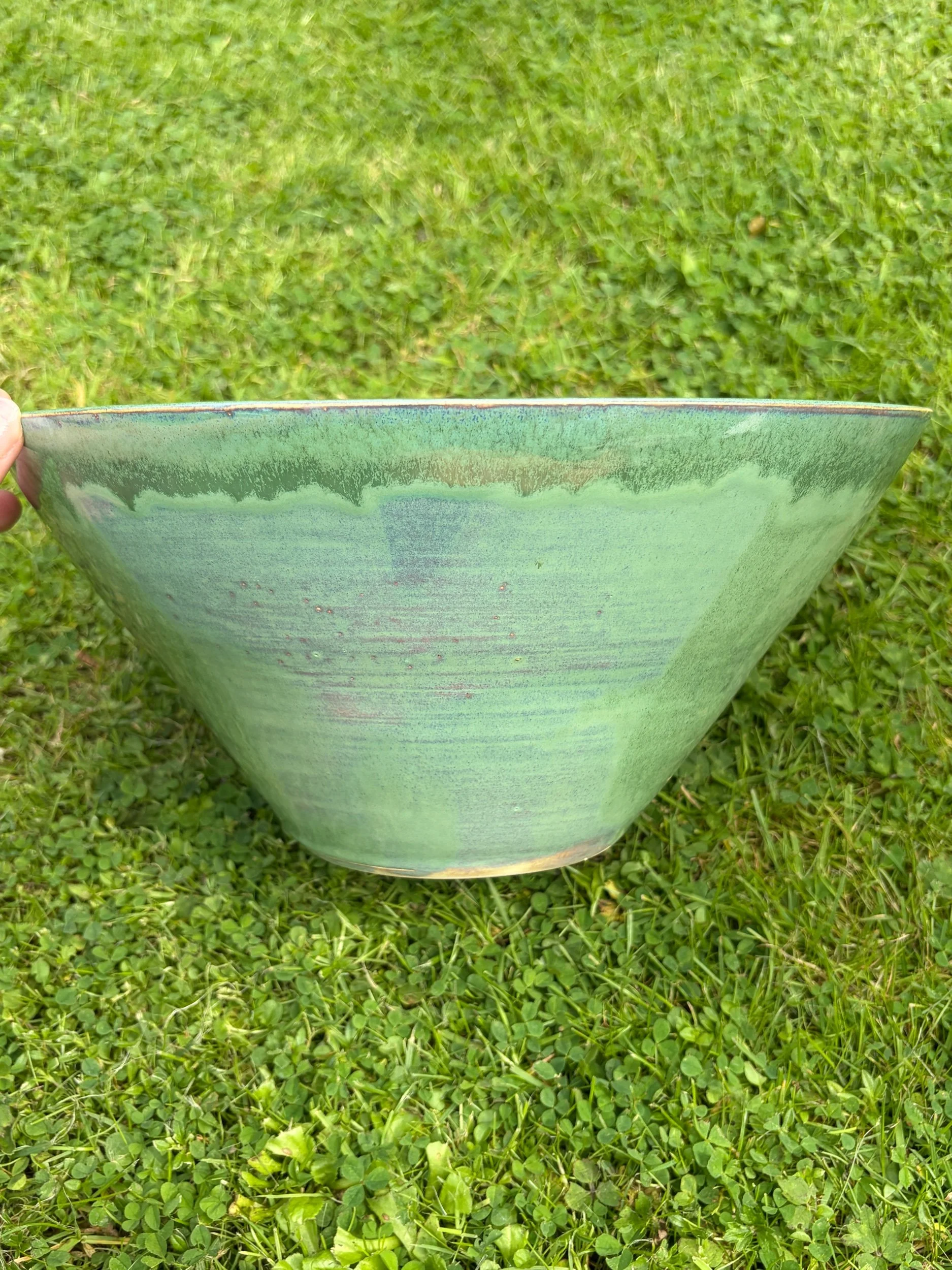 Large V shaped bowl in pistachio glaze with white satin interior glaze pictured on grass