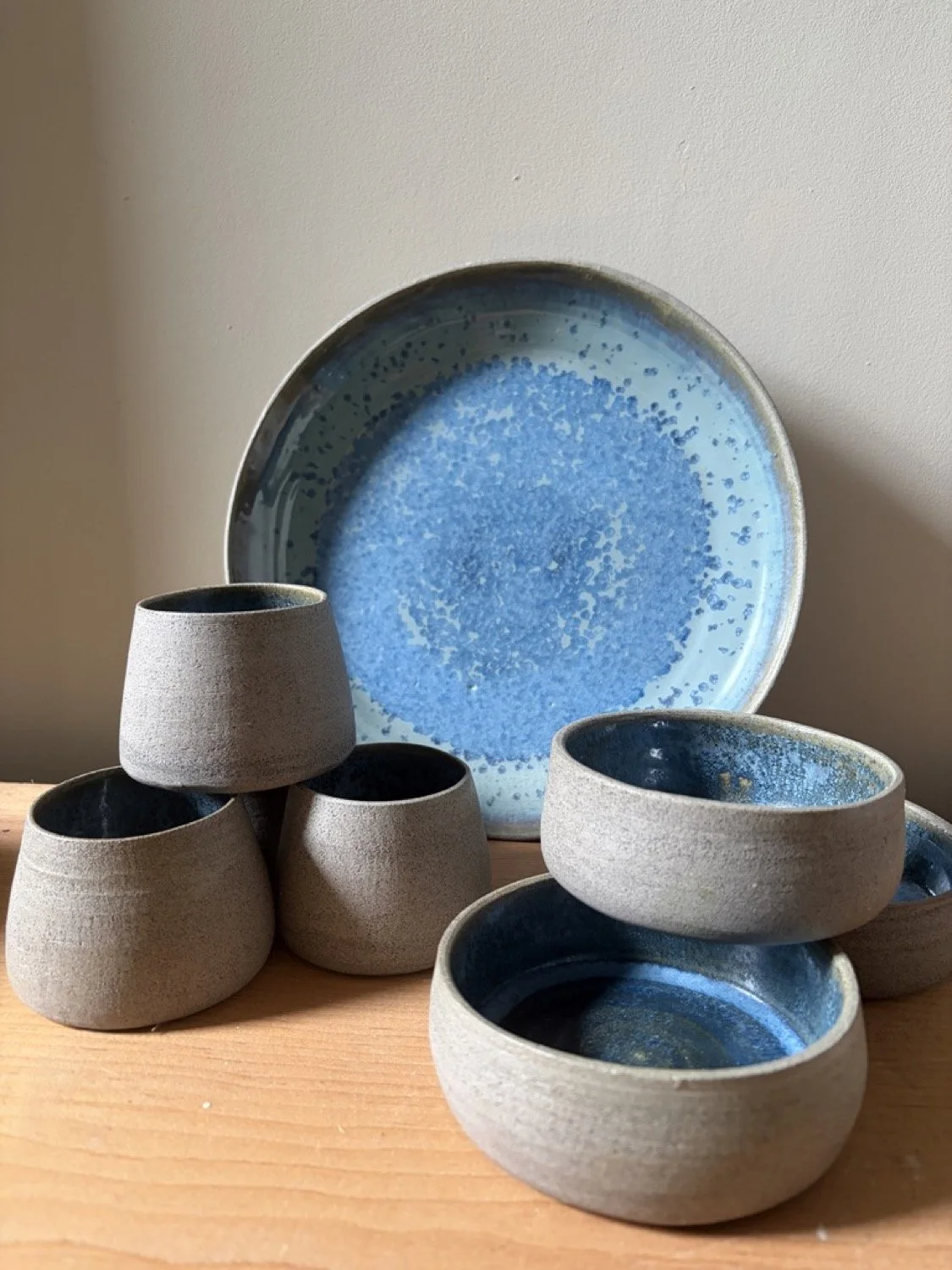 Handcrafted pottery with a handleless cup in glacier glaze image shows a plate and a set of cups