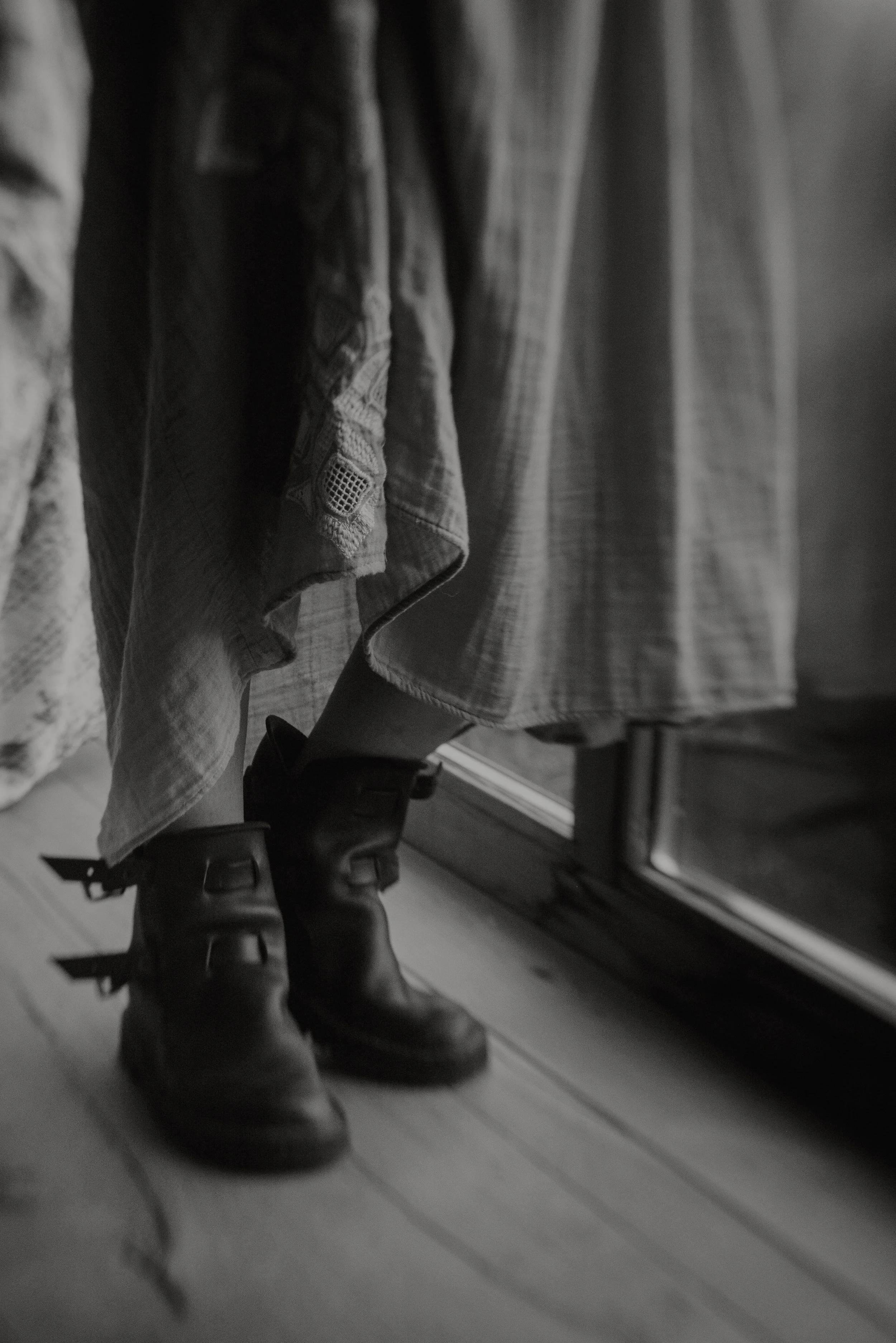 Close-up van schoenen, met Sietske die in de achtergrond voor een raam staat in haar coach praktijk