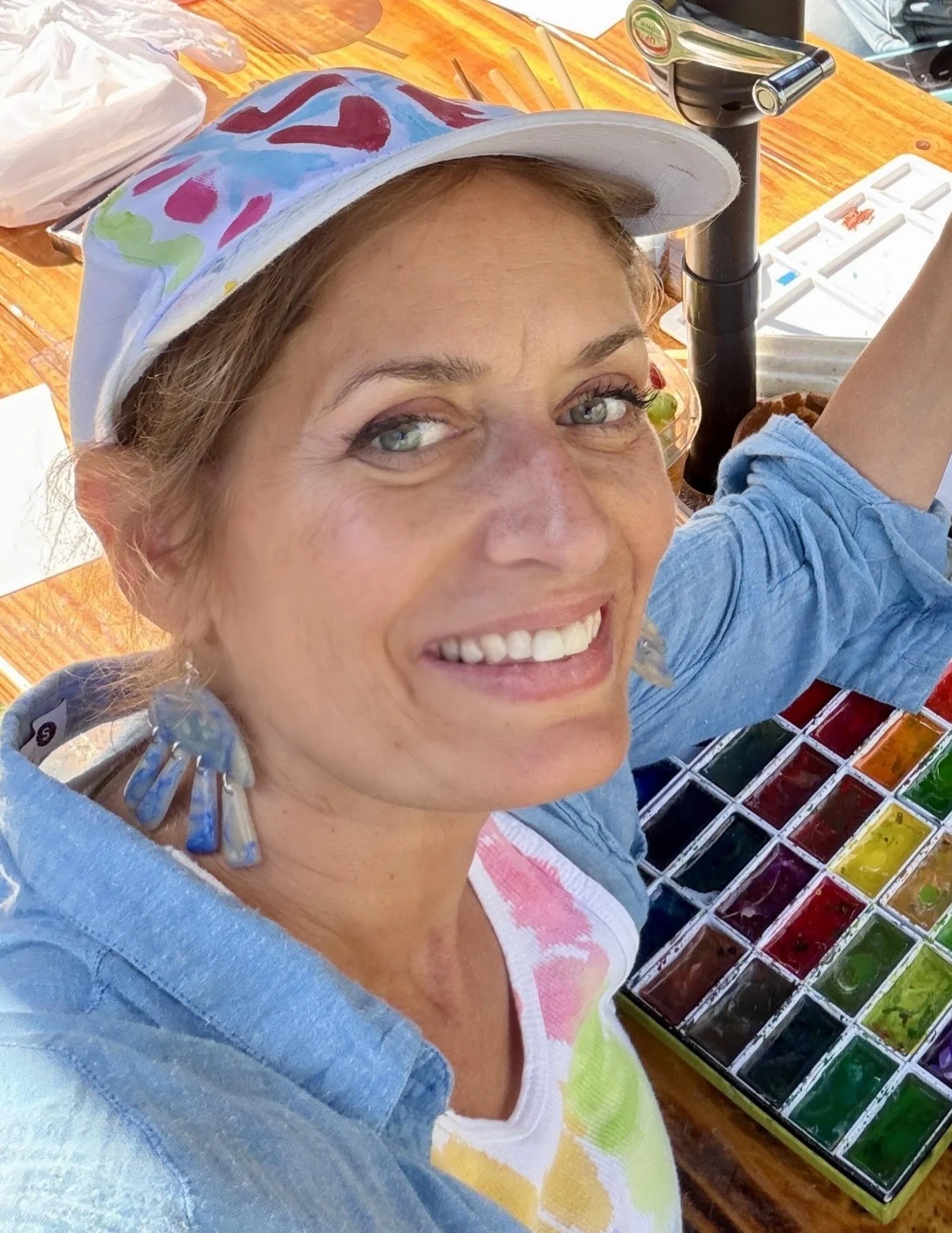 Close-up photo of a smiling woman with light brown and reddish hair, wearing a light blue shirt.