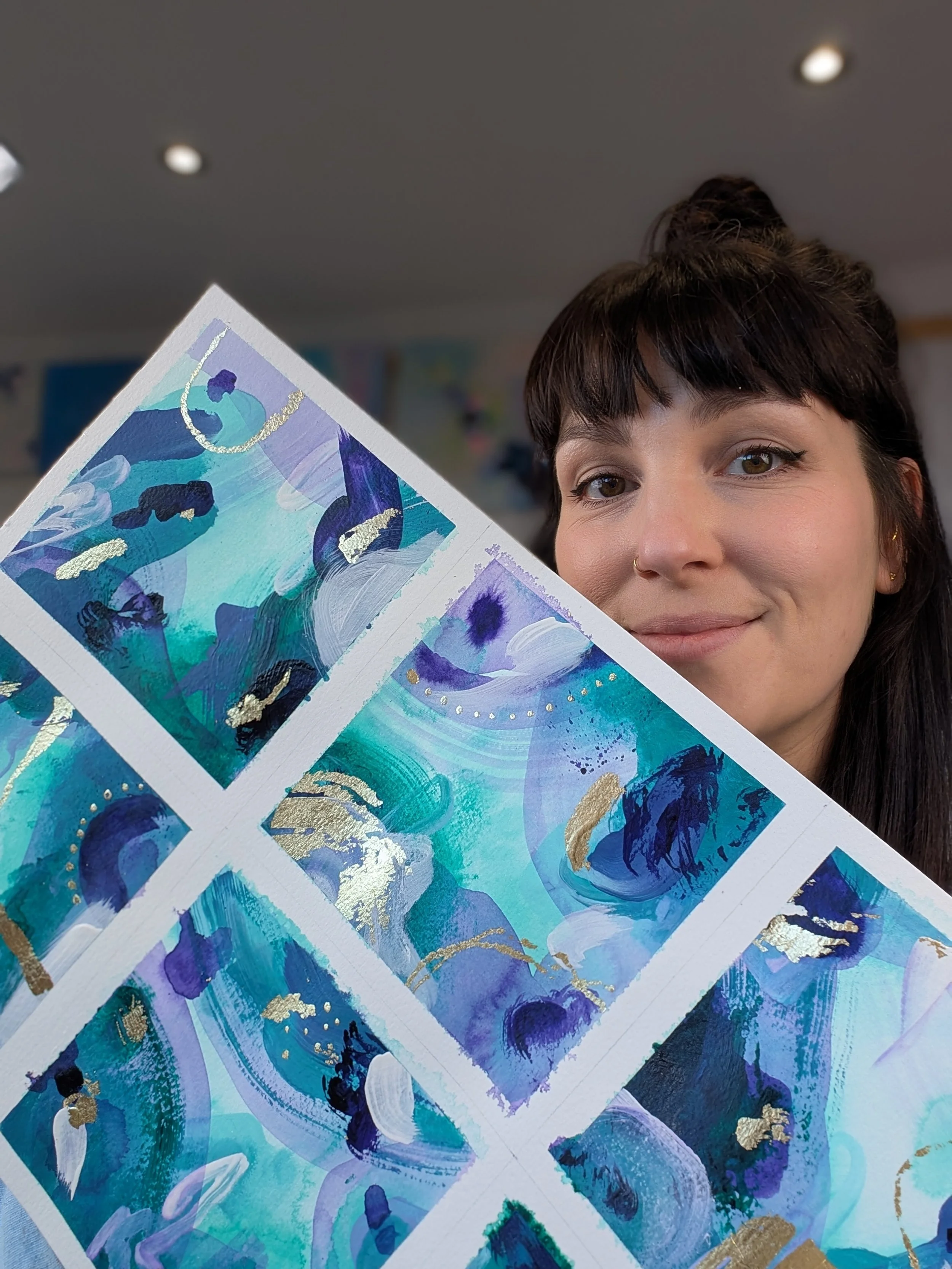 Artist Victoria Hough holding examples of her abstract painting studies