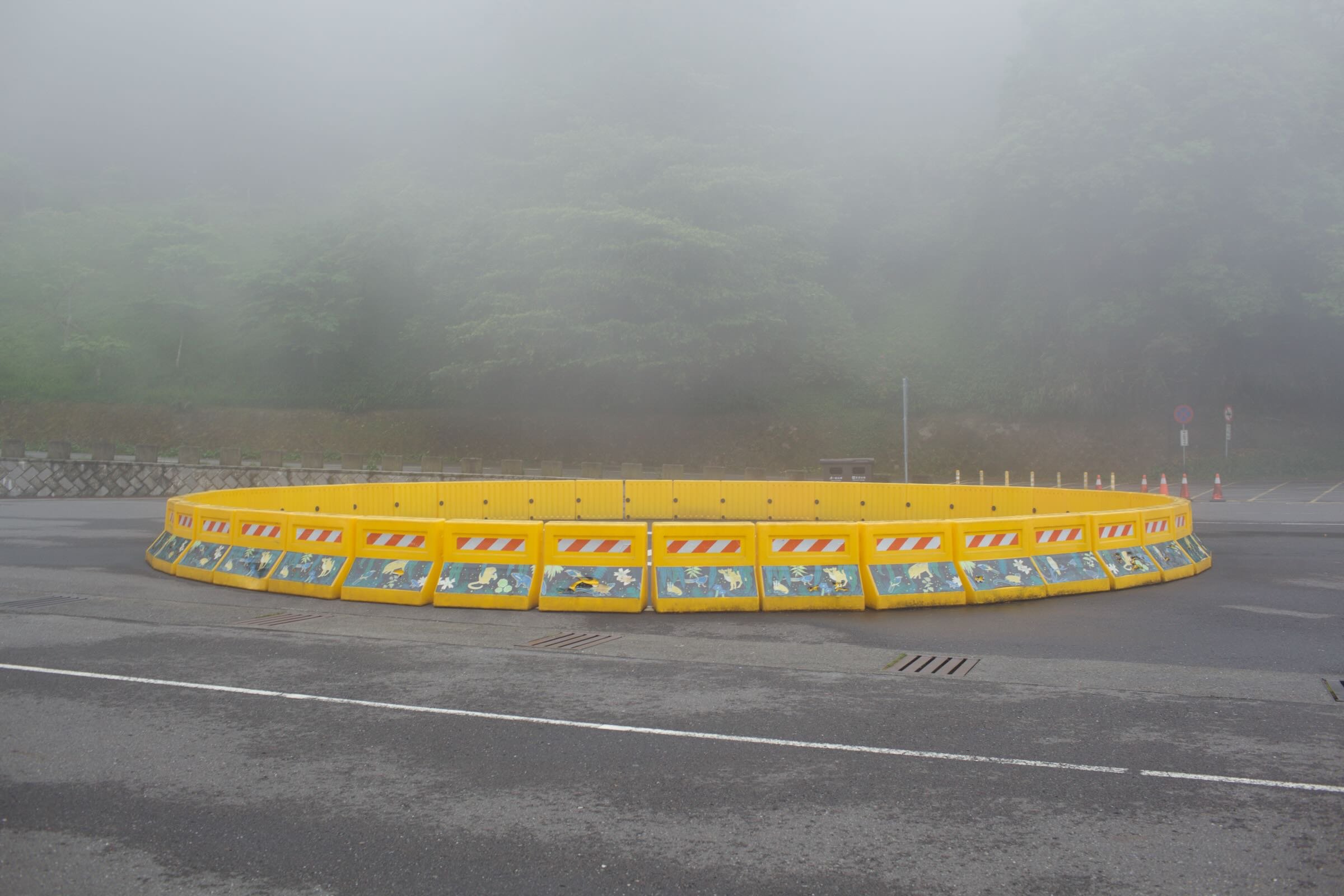 Yellow circular traffic barrier on foggy road