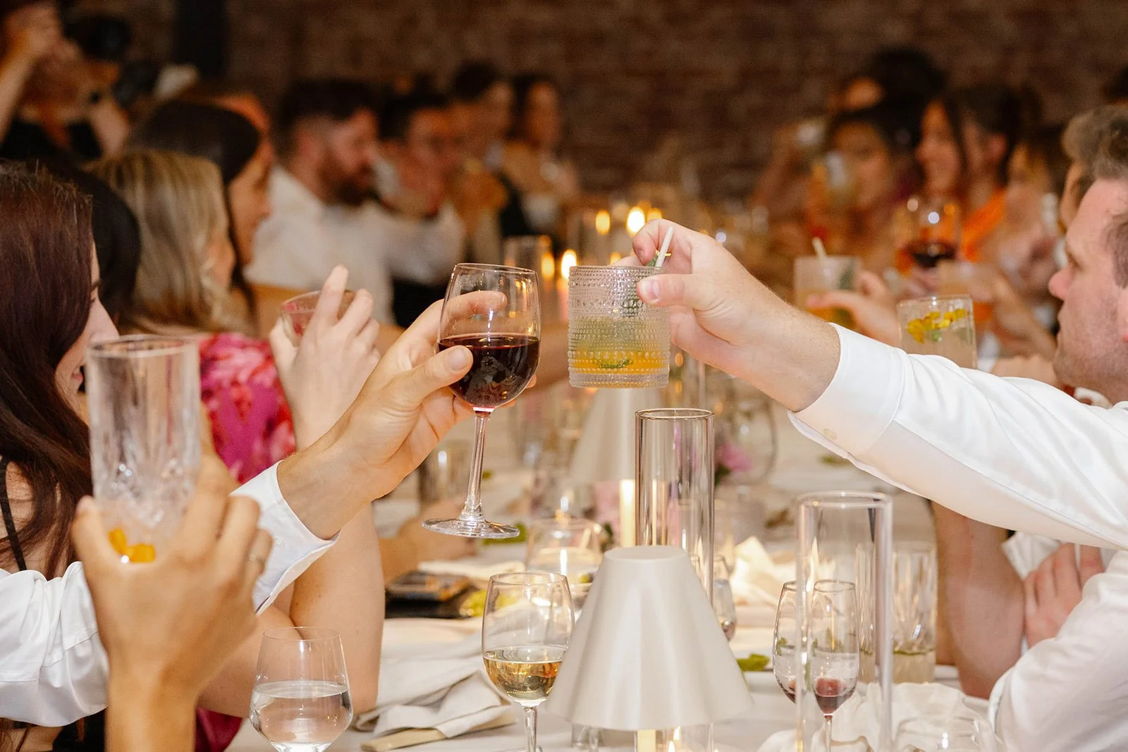 Wedding reception tablescape with guests raising cocktails