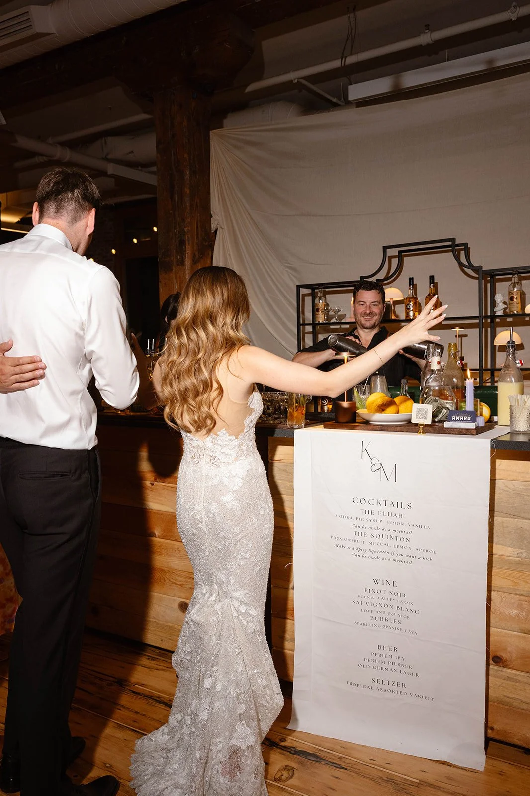 Bride reaching for a drink from bartender at wedding reception 