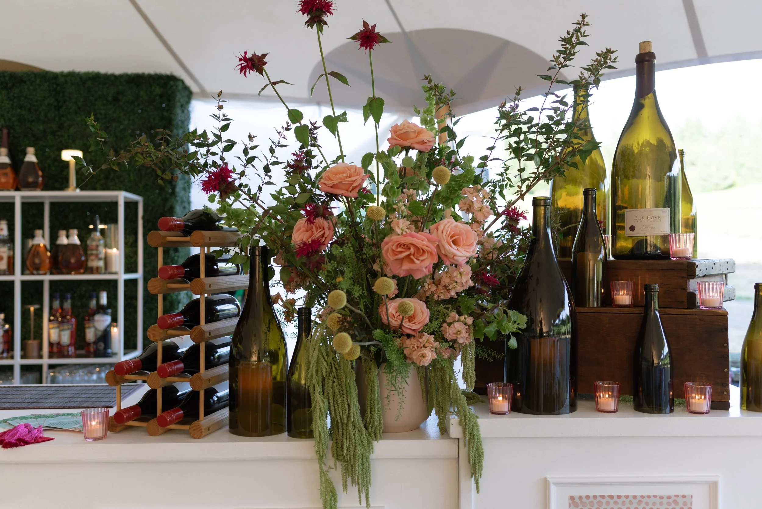 Bar set up with flowers and wine glasses, curated by Amaro Bartending, a cocktail catering service.