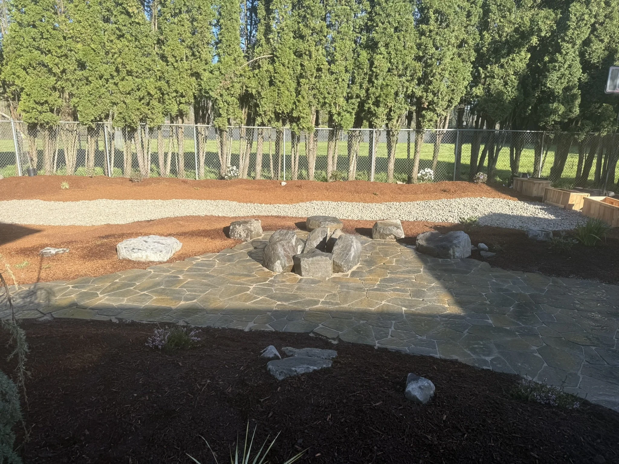 Fire pit, barkdust, boulders, plantings, stone. 