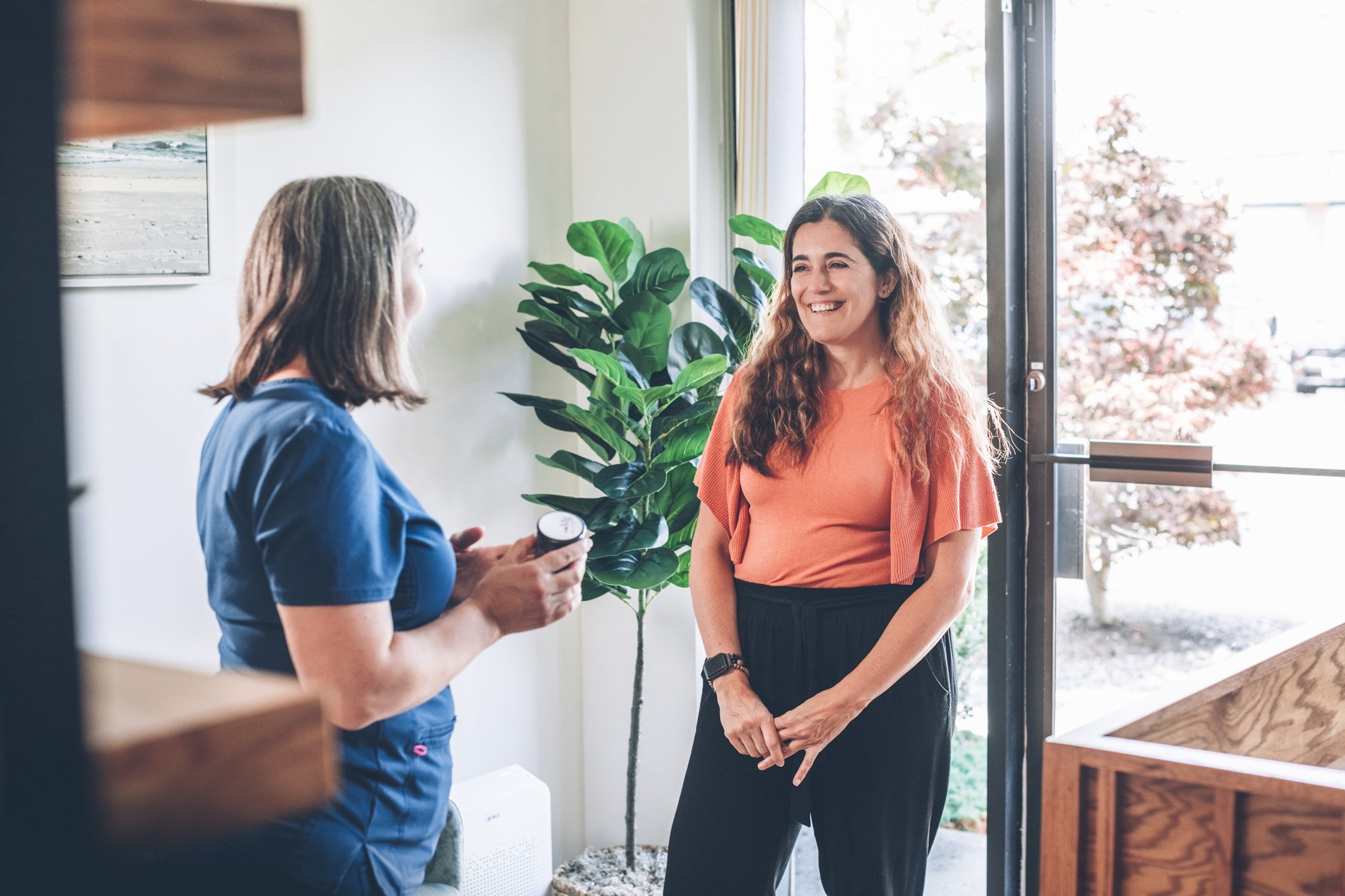Acupuncturist speaking with a smiling patient during an initial consultation.