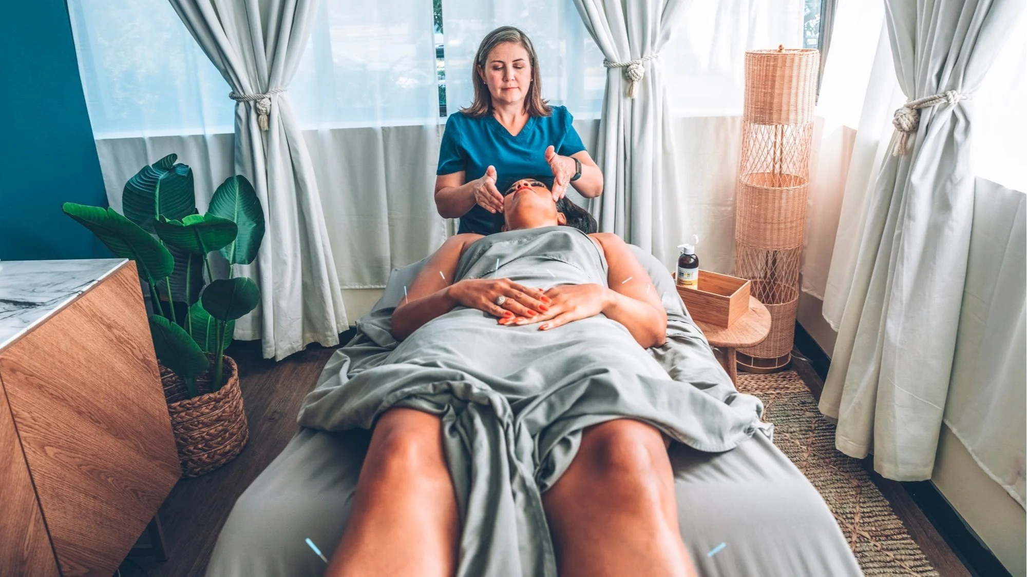 Maureen Giese, DACM performing facial massage while a patient rests during an acupuncture session.