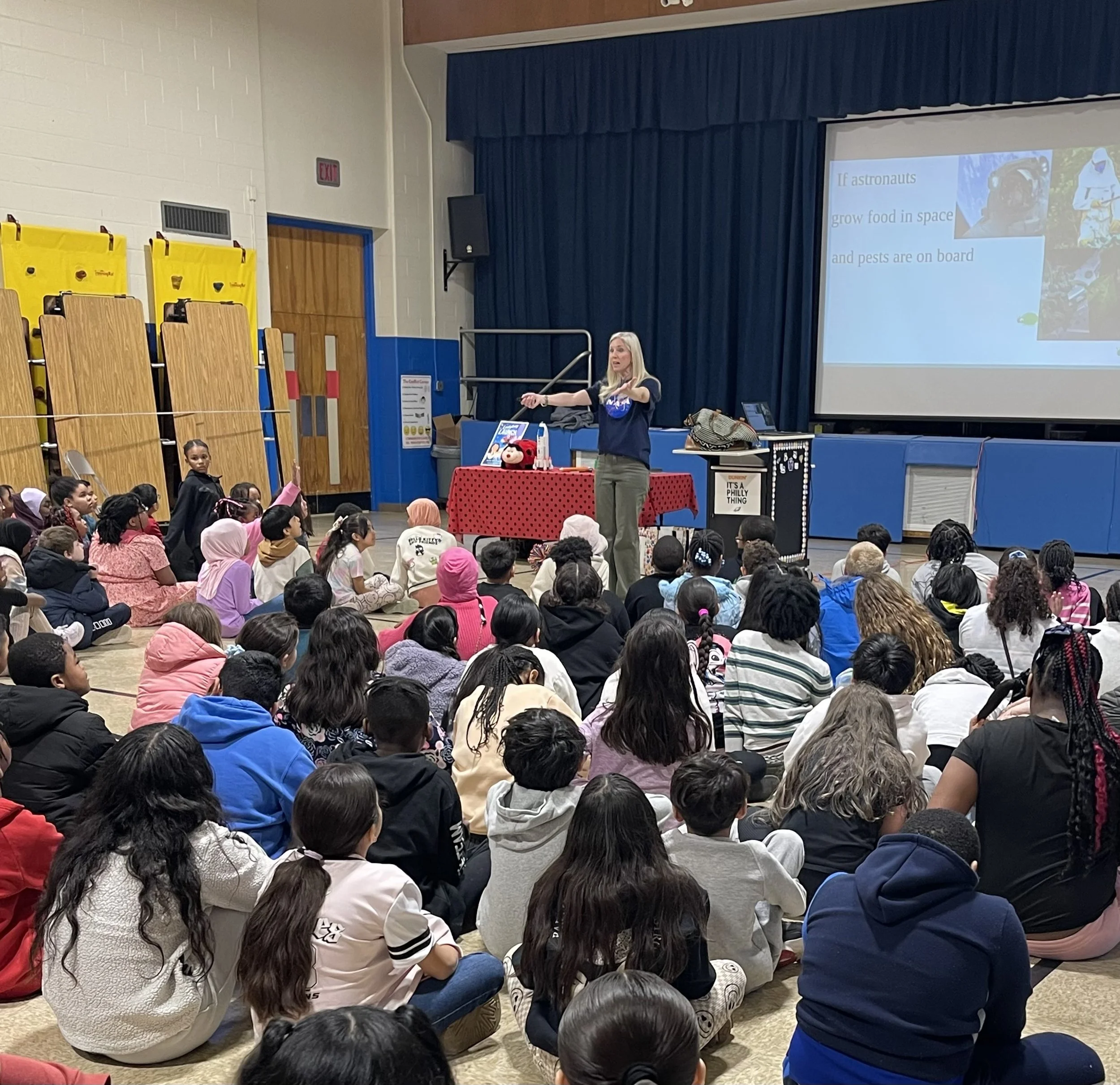 Melissa Trempe doing an author visit assembly to a large group of students at an elementary school.