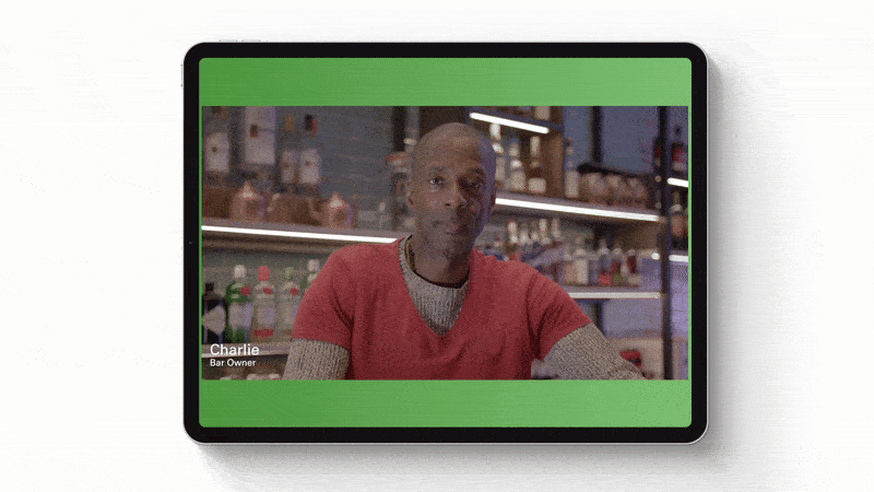 A tablet displaying a live video call with a man named Charlie, a bar owner, sitting at a bar with bottles in the background.