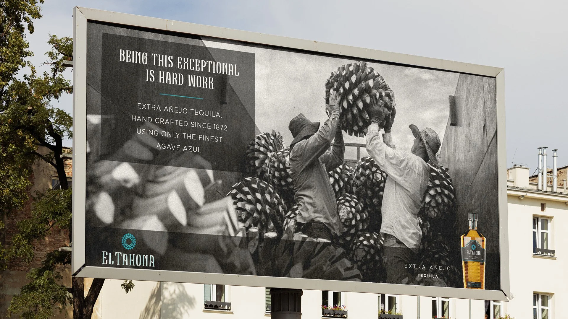 Billboard advertisement for El Tahoma extra añejo tequila featuring black and white photos of workers handling agave plants with a bottle of tequila in the bottom right corner.