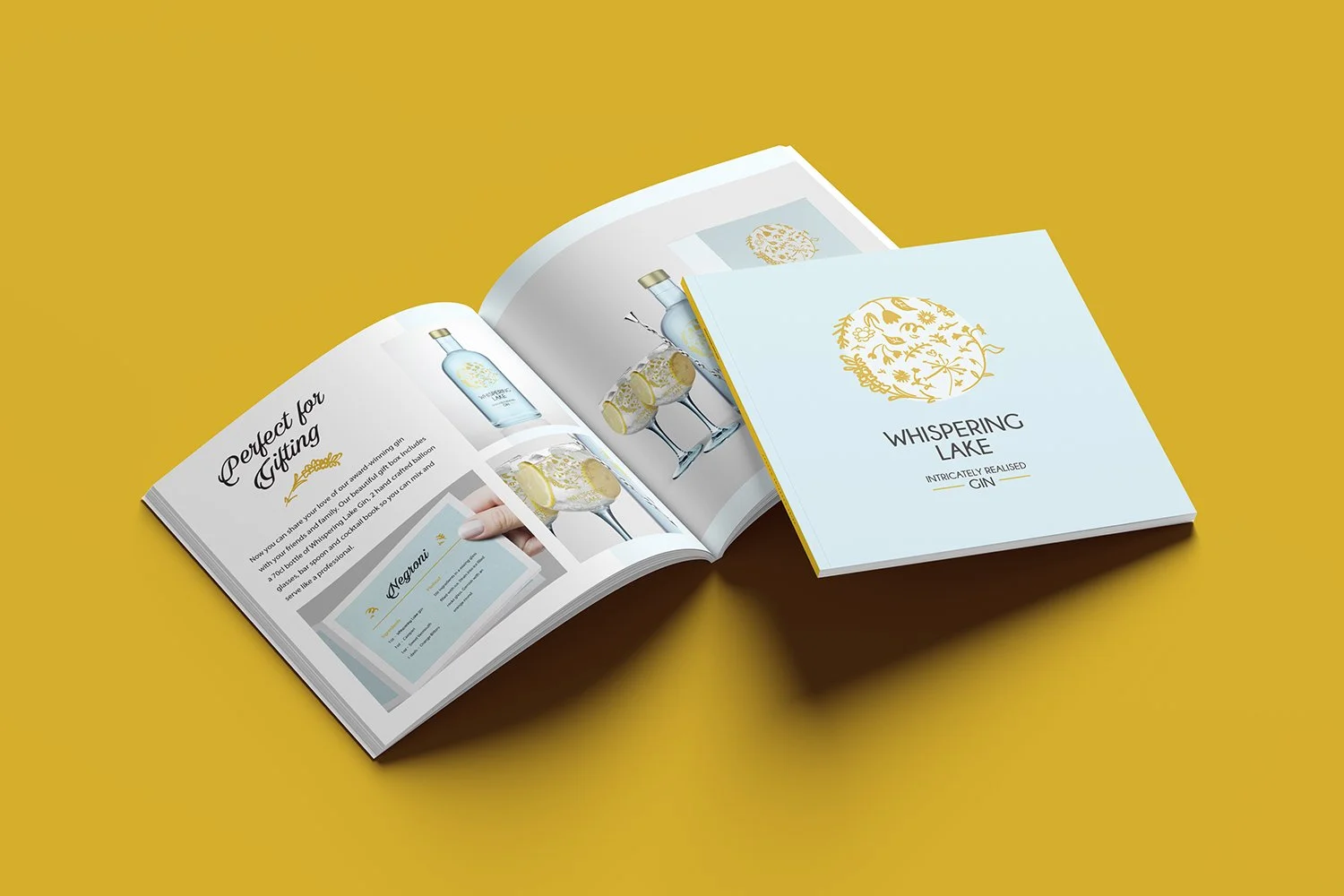 Open brochure displaying a bottle of Whispering Lake gin and pictures of gin and tonic drinks garnished with lemon slices, on a yellow background.