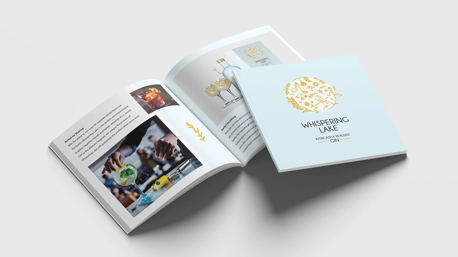 Open magazine featuring images of cocktails and drinks, with the cover titled 'Whispering Lake' and the subtitle 'Intricately Realized Gin'.