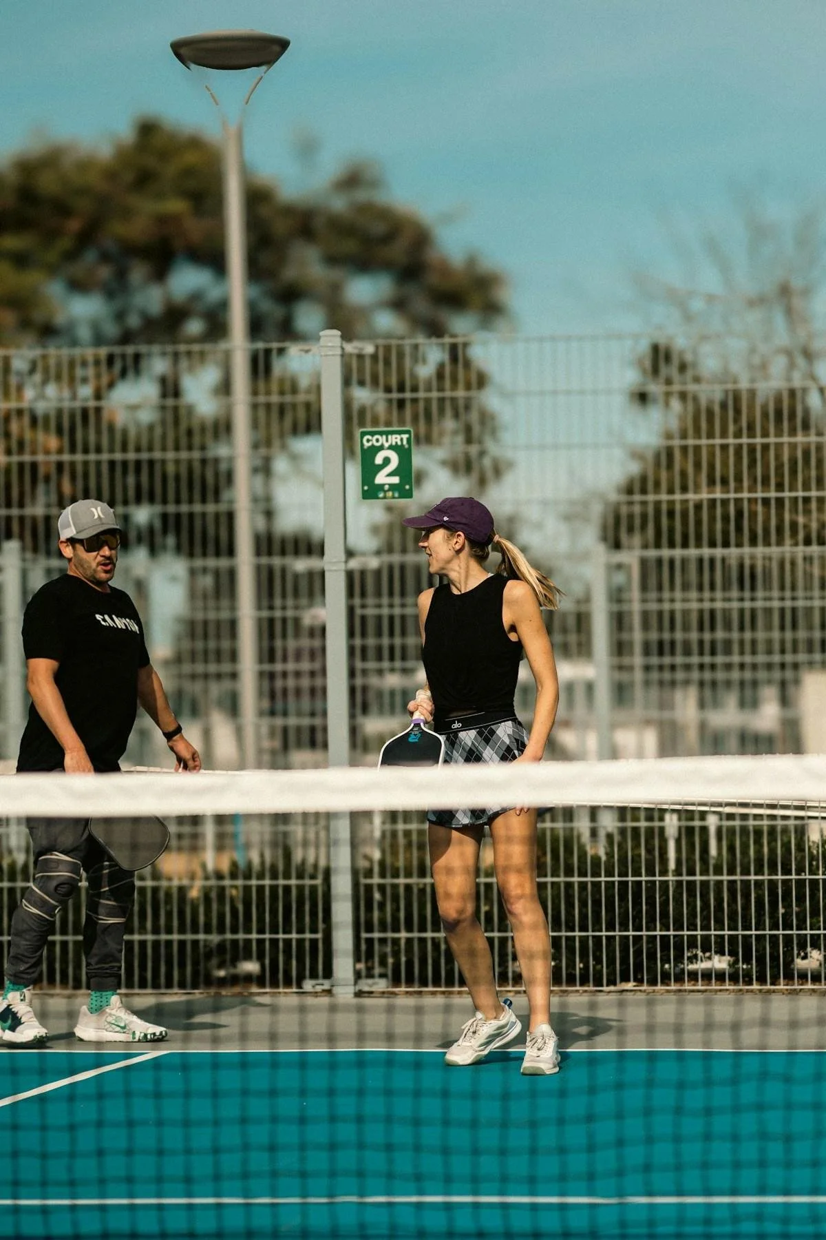 couple in late 40's playing pickleball on an outdoor court looking happy and fit.