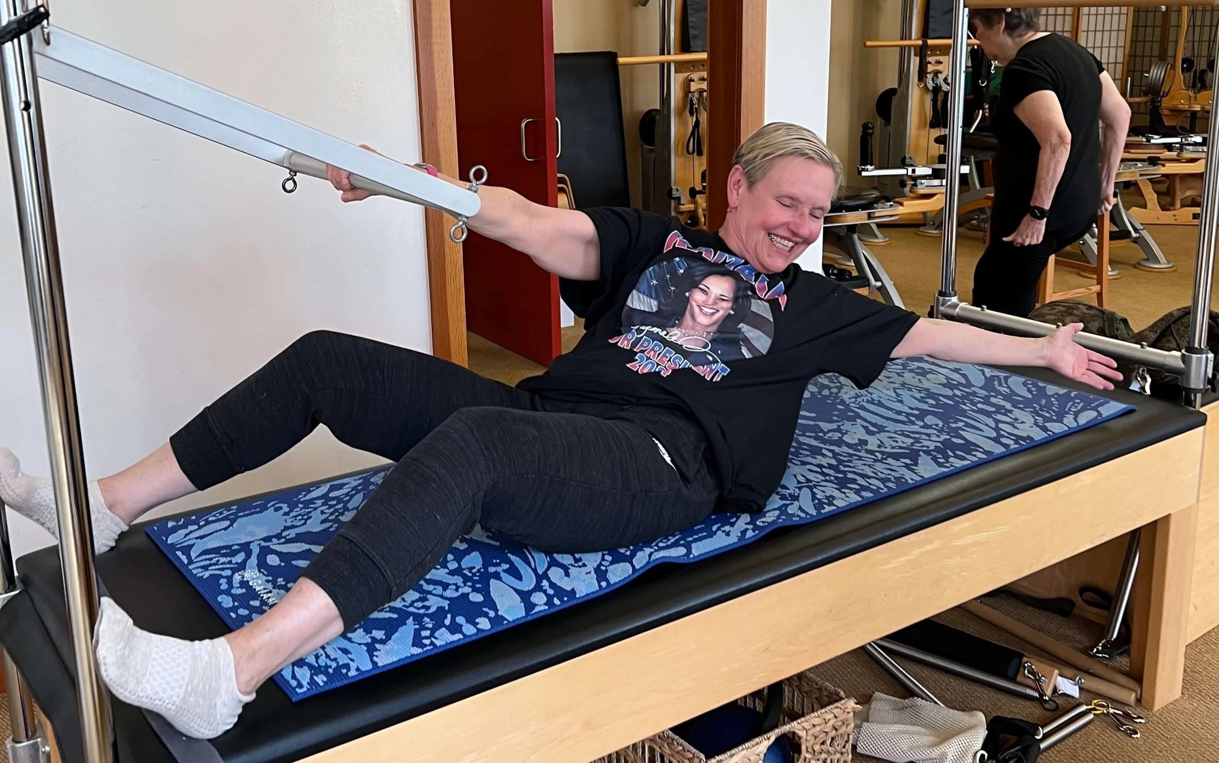 Woman in her 60s on a Pilates Cadillac machine stretching