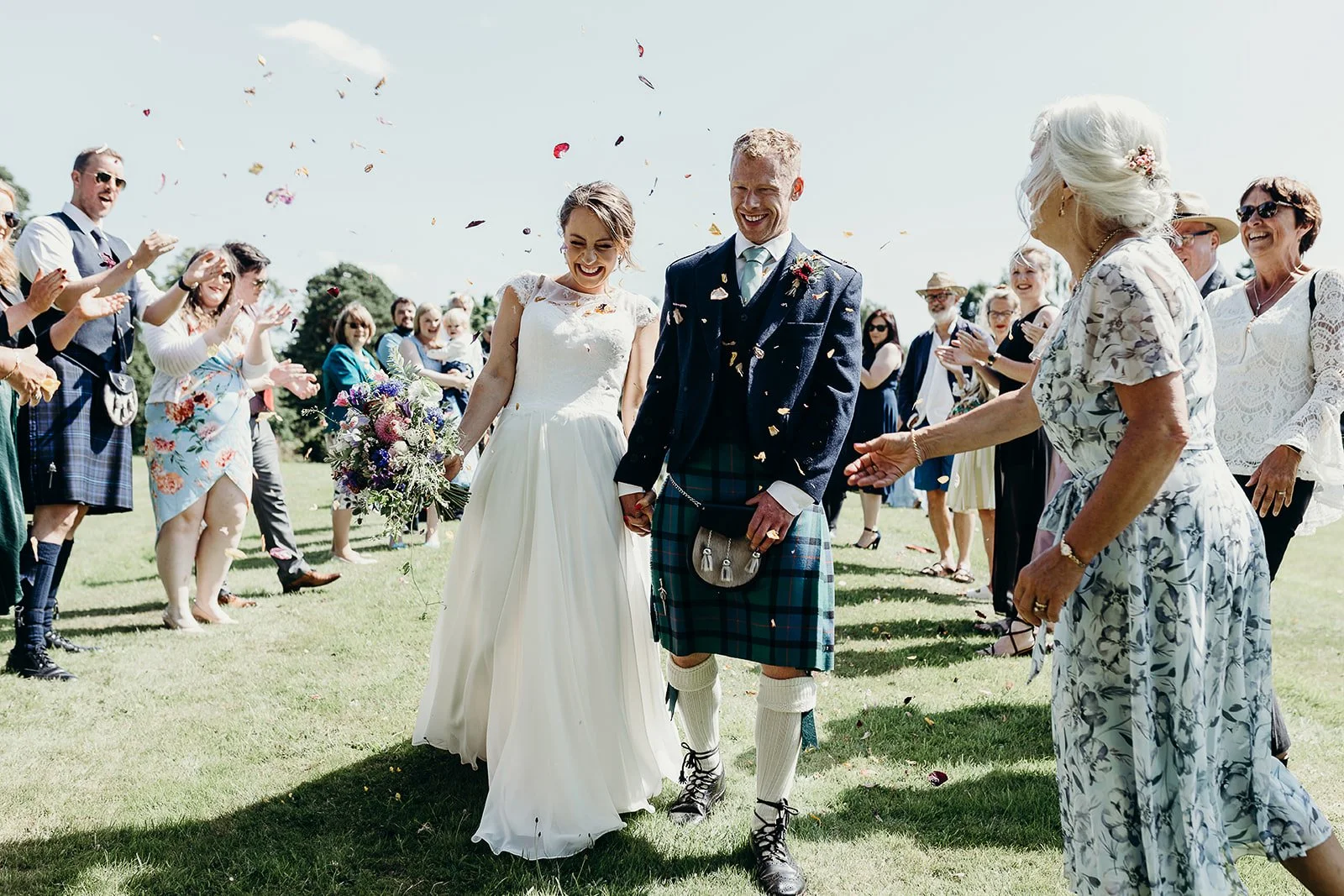 Bride and groom walking hand in hand after their wedding ceremony, surrounded by friends and family celebrating with confetti and cheerful expressions