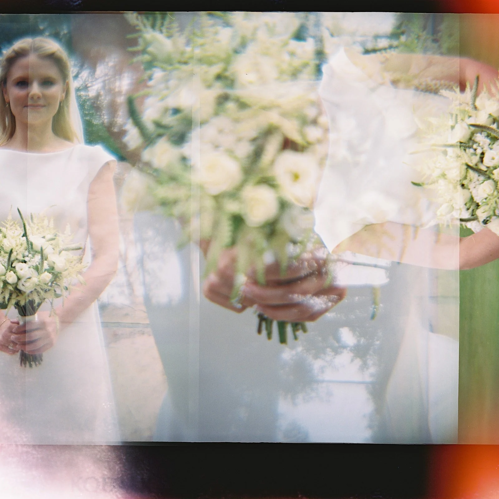 A woman in a white dress holding a bouquet of white flowers. The photo appears double-exposed with her reflection and a person's hands holding a similar bouquet.