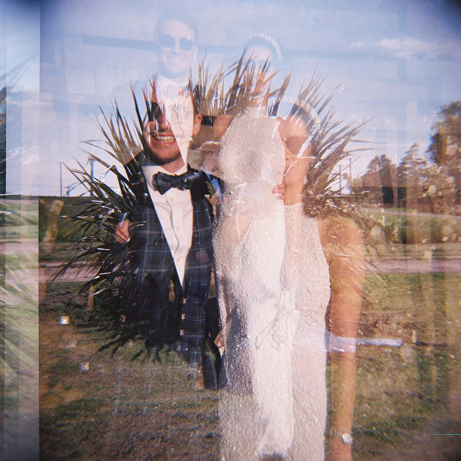 A layered, transparent image of a wedding couple standing outdoors, with the man in a tuxedo and the woman in a wedding dress, both smiling.
