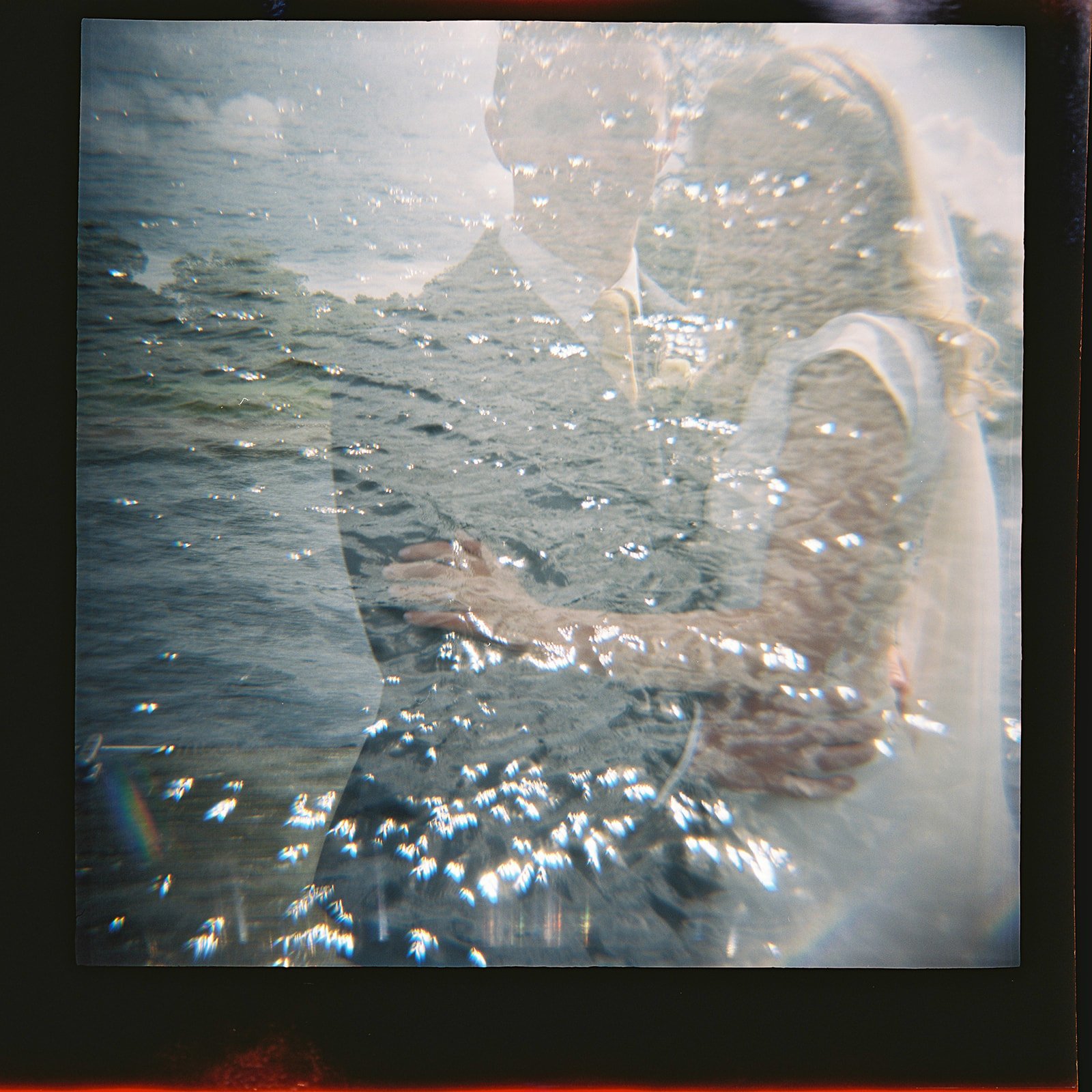 A double exposure photograph combining an image of a person wearing glasses, a cap, and a hoodie with an image of a body of water with small waves.
