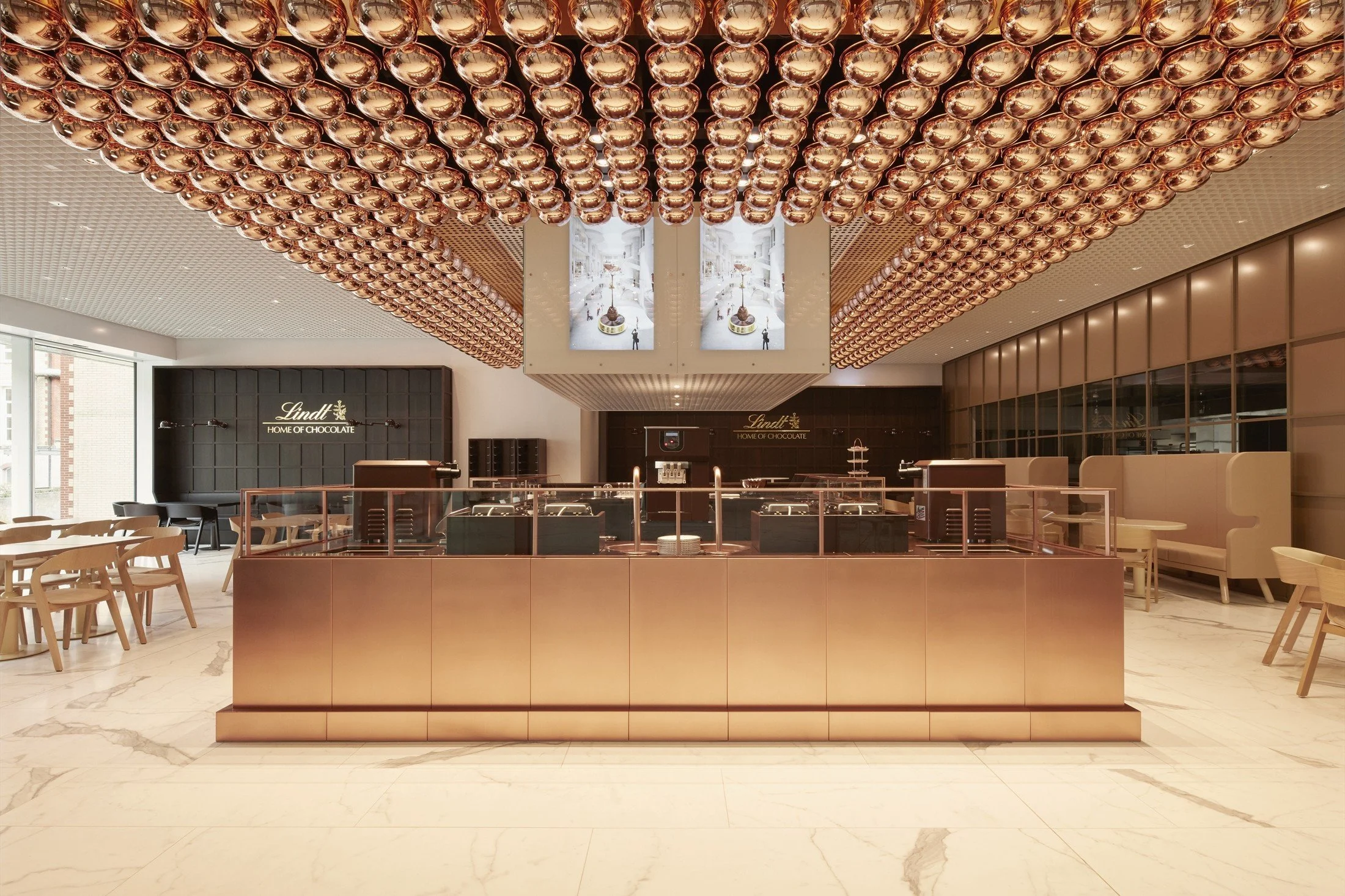 Lindt Home of Chocolate café counter beneath a ceiling of copper-toned decorative spheres.