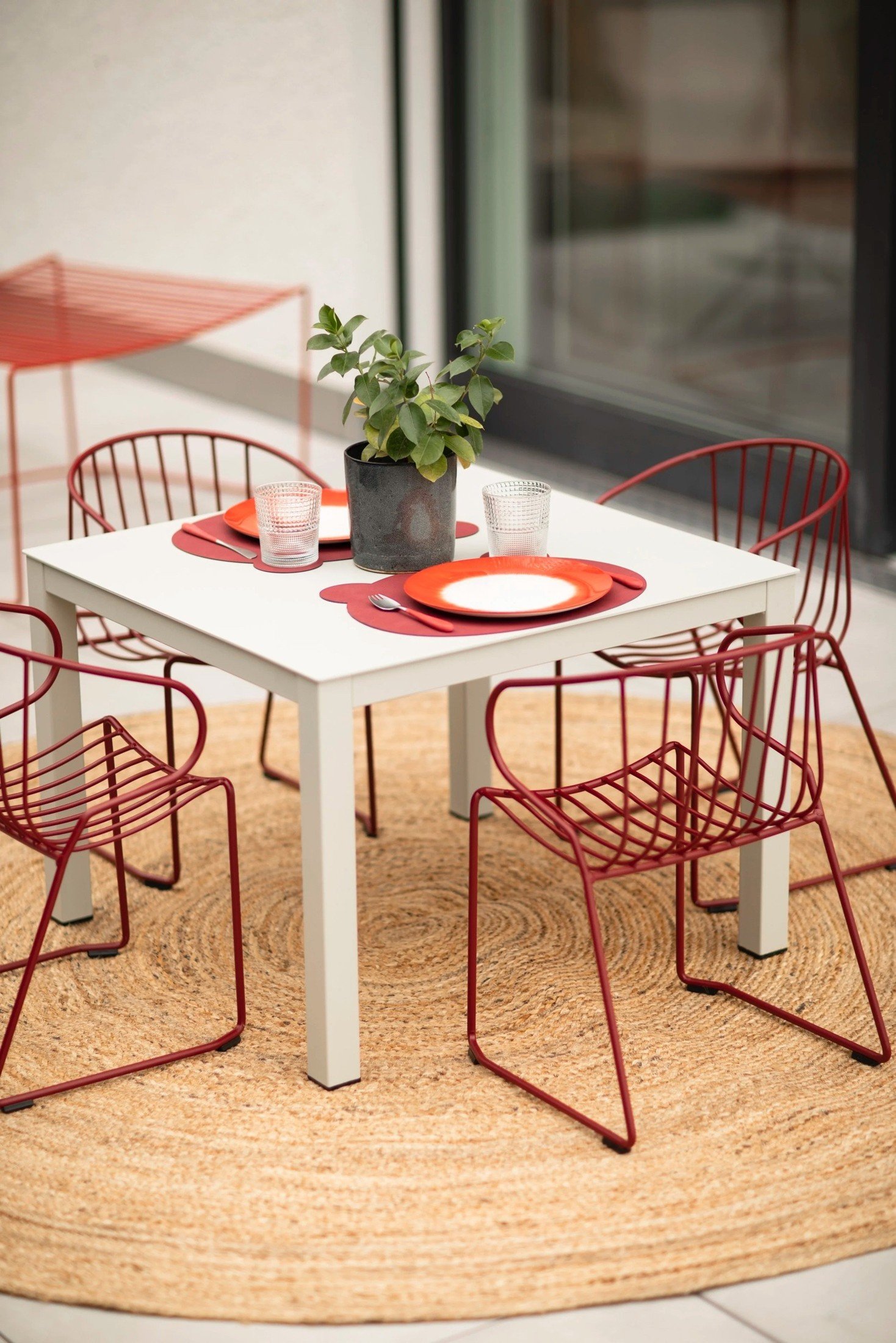 Horgen terrace dining area with red outdoor chairs and a white table.