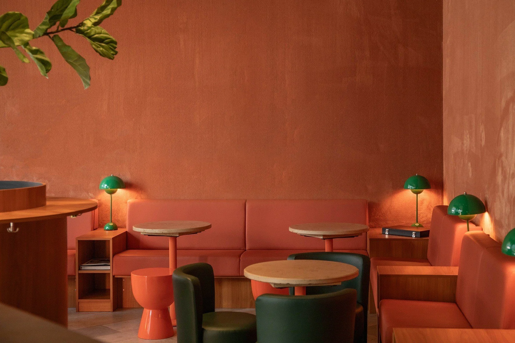 Le Café seating concept with orange chairs, small round tables and a warm vintage-inspired palette.