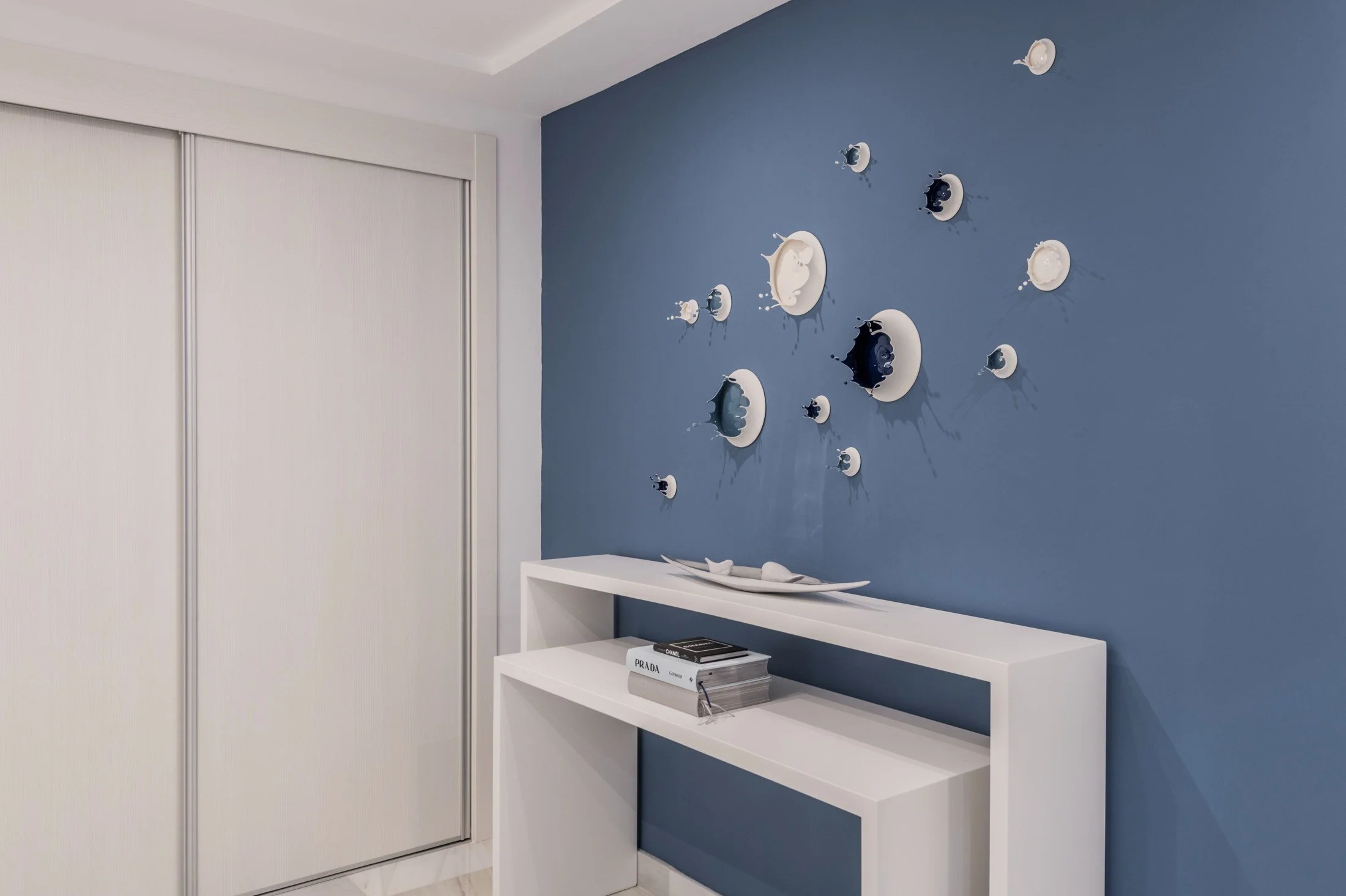 Blue feature wall with decorative mirrors above a pale console in the Marbella home.
