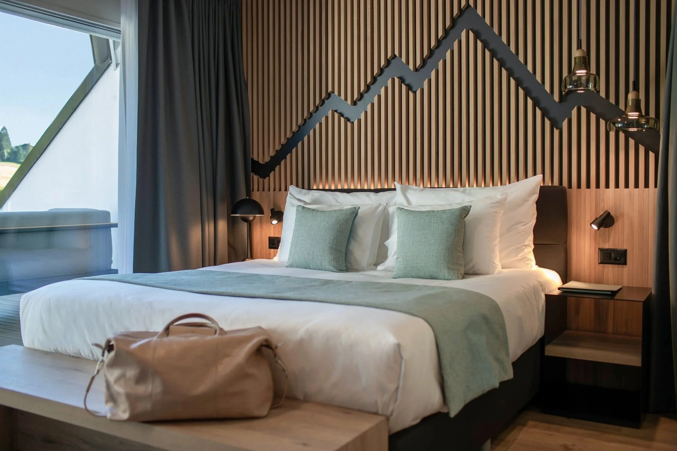 Swiss Holiday Park guest room showing the bed, seating area and mountain-inspired timber feature wall.
