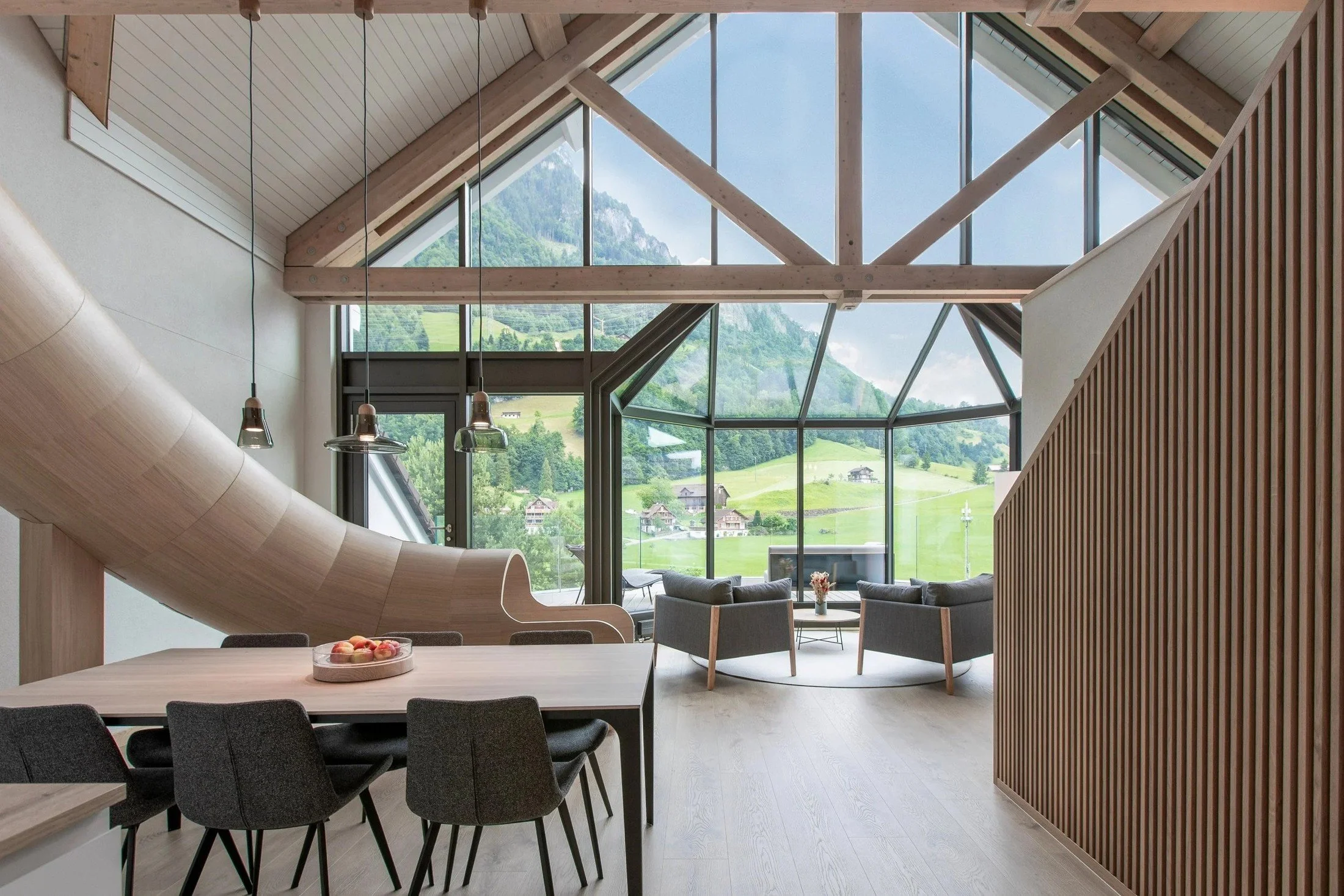 Resort dining and lounge space with exposed timber structure and large windows overlooking greenery.