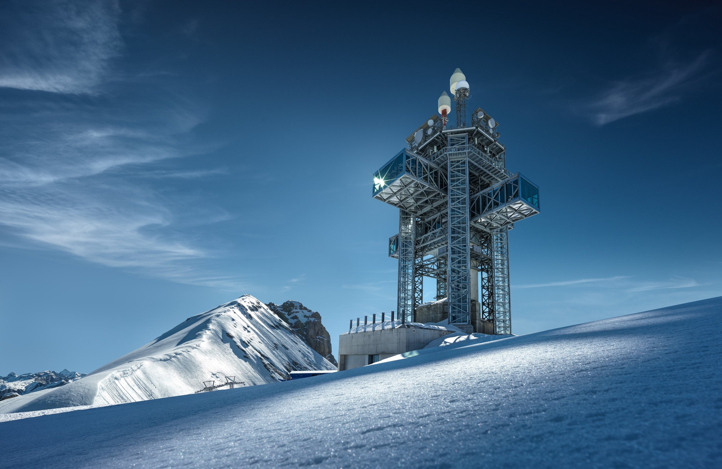 Titlis tower rising above a snow-covered Alpine ridge.