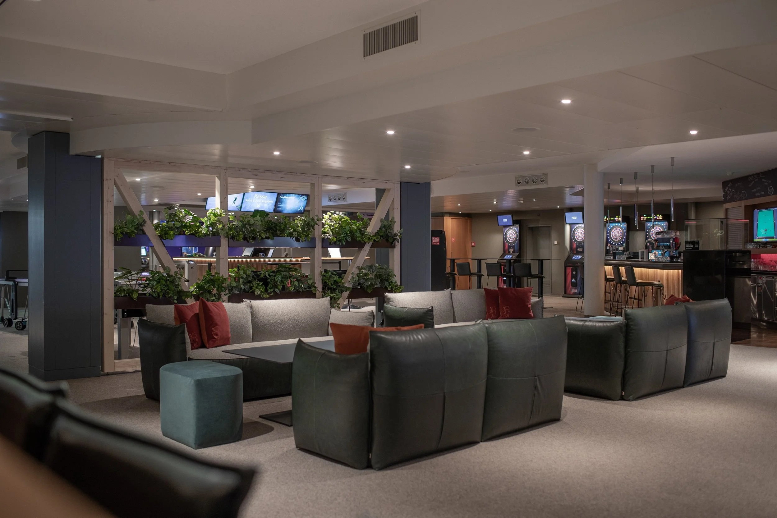 Sportsbar entertainment area with grouped lounge seating, low tables and warm ambient lighting.