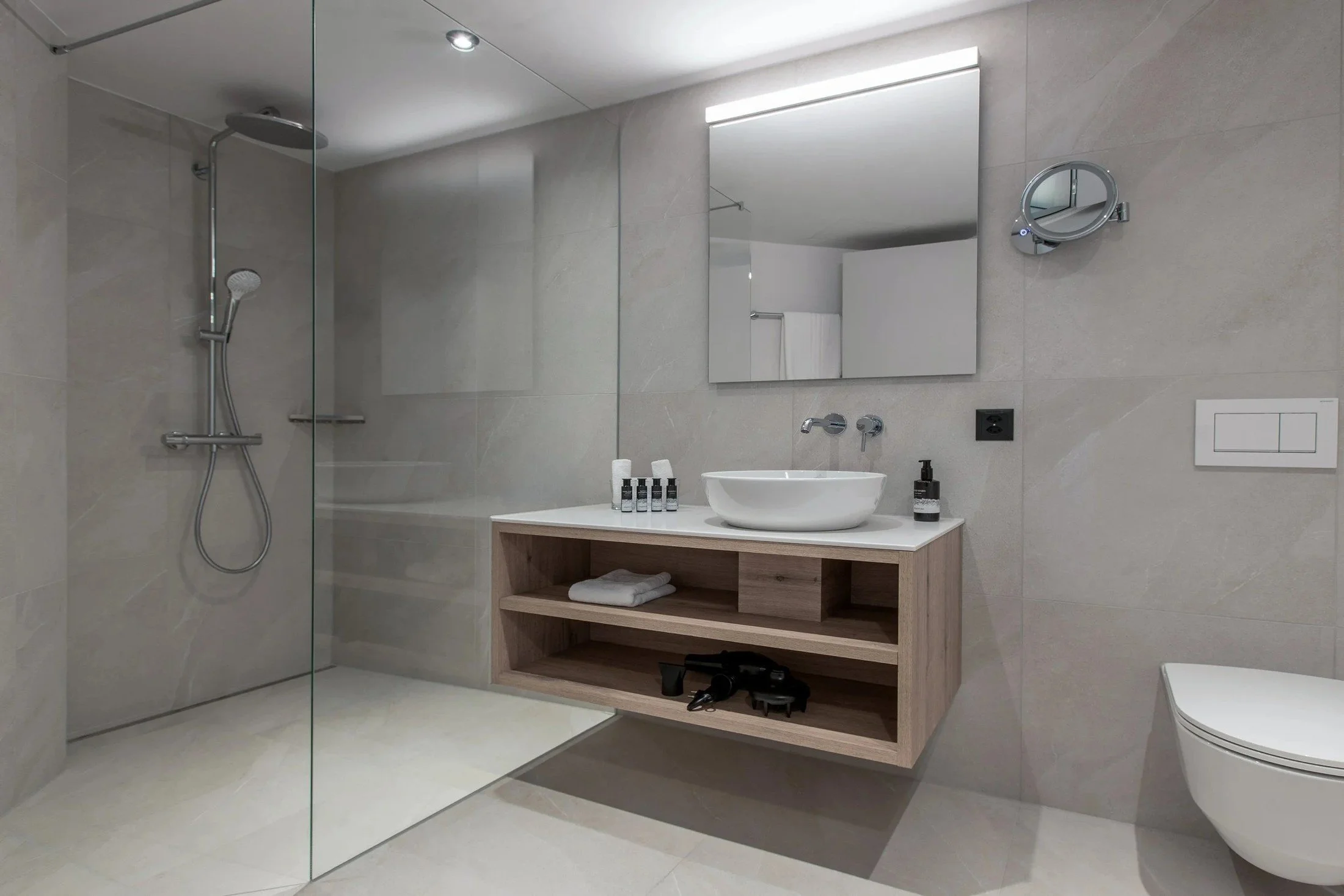 Renovated resort bathroom with a wide vanity, illuminated mirror and neutral finishes.
