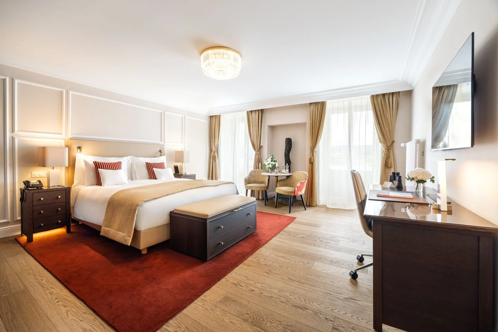 Renovated hotel suite with upholstered seating, a writing desk and layered neutral finishes.