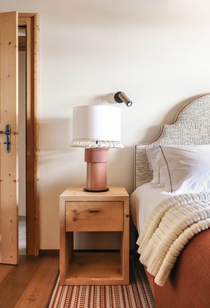 Bedroom detail with an upholstered headboard, timber bedside table and reading lamp.