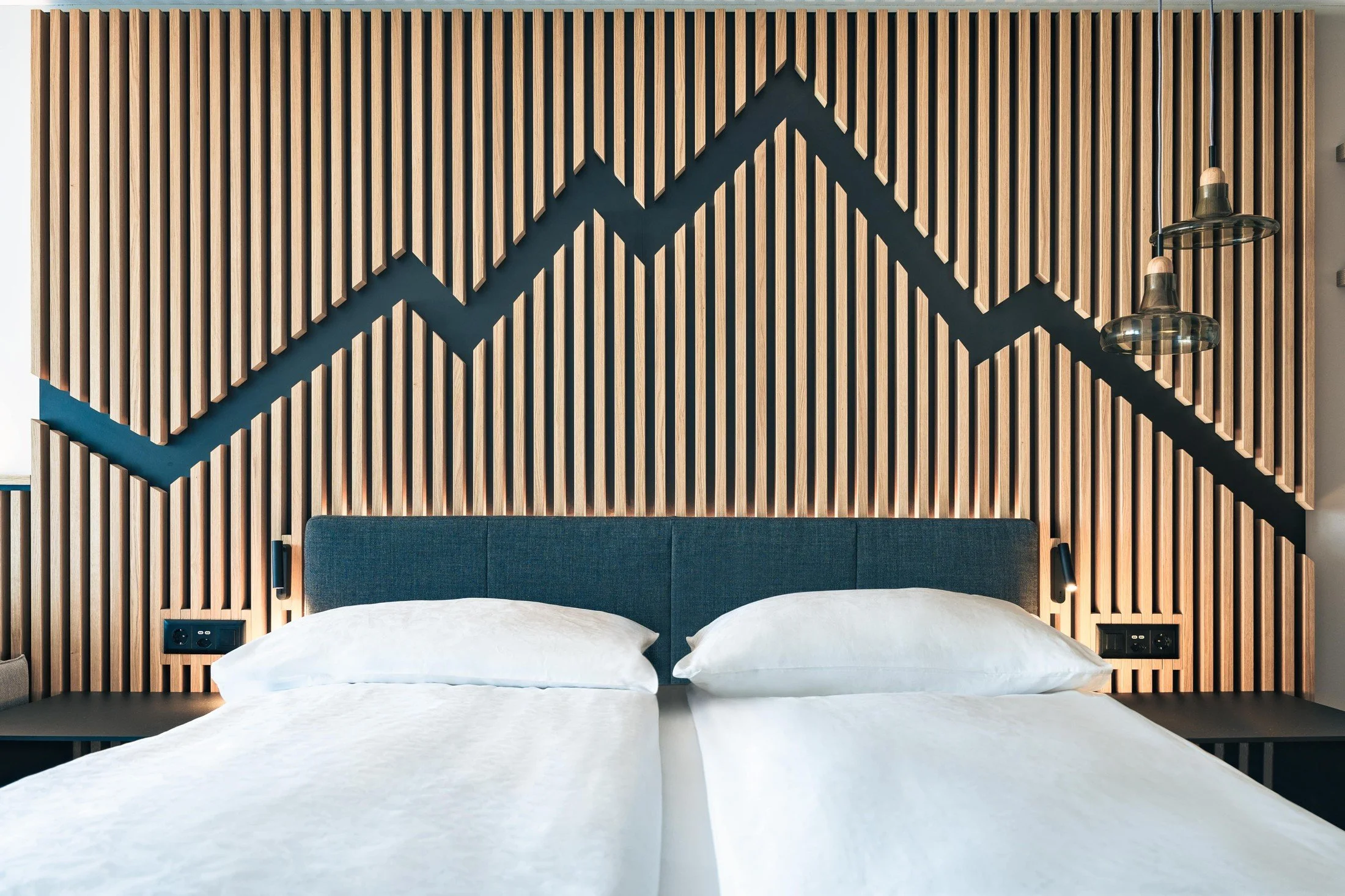 Swiss Holiday Park guest bedroom with a timber slat headboard and a blue mountain outline above the bed.