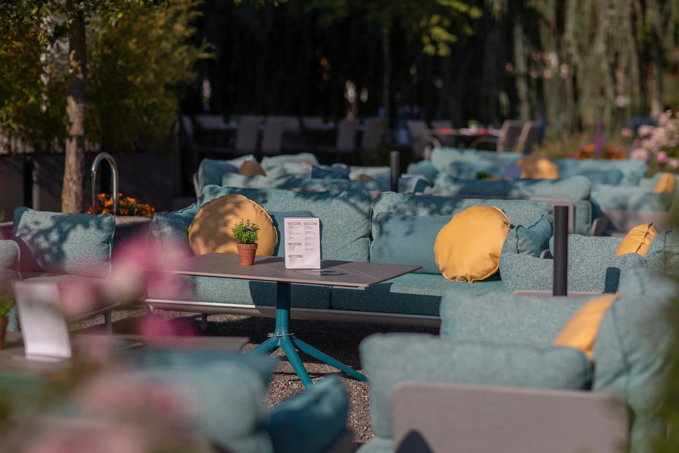 Siam Restaurant lounge terrace with teal seating, patterned cushions and bright yellow accents.