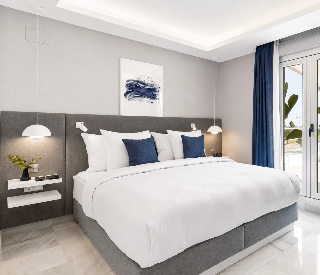 Holiday home bedroom with white bedding, blue accents and a padded headboard.