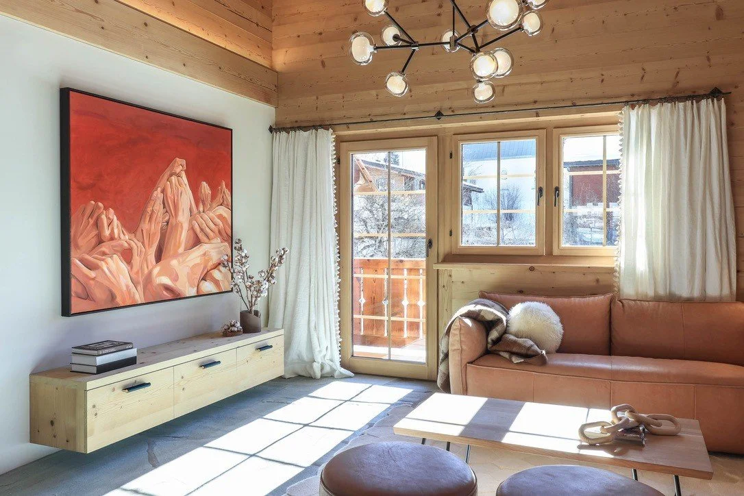 Warm Alpine living room with timber finishes, colourful artwork and generous windows.