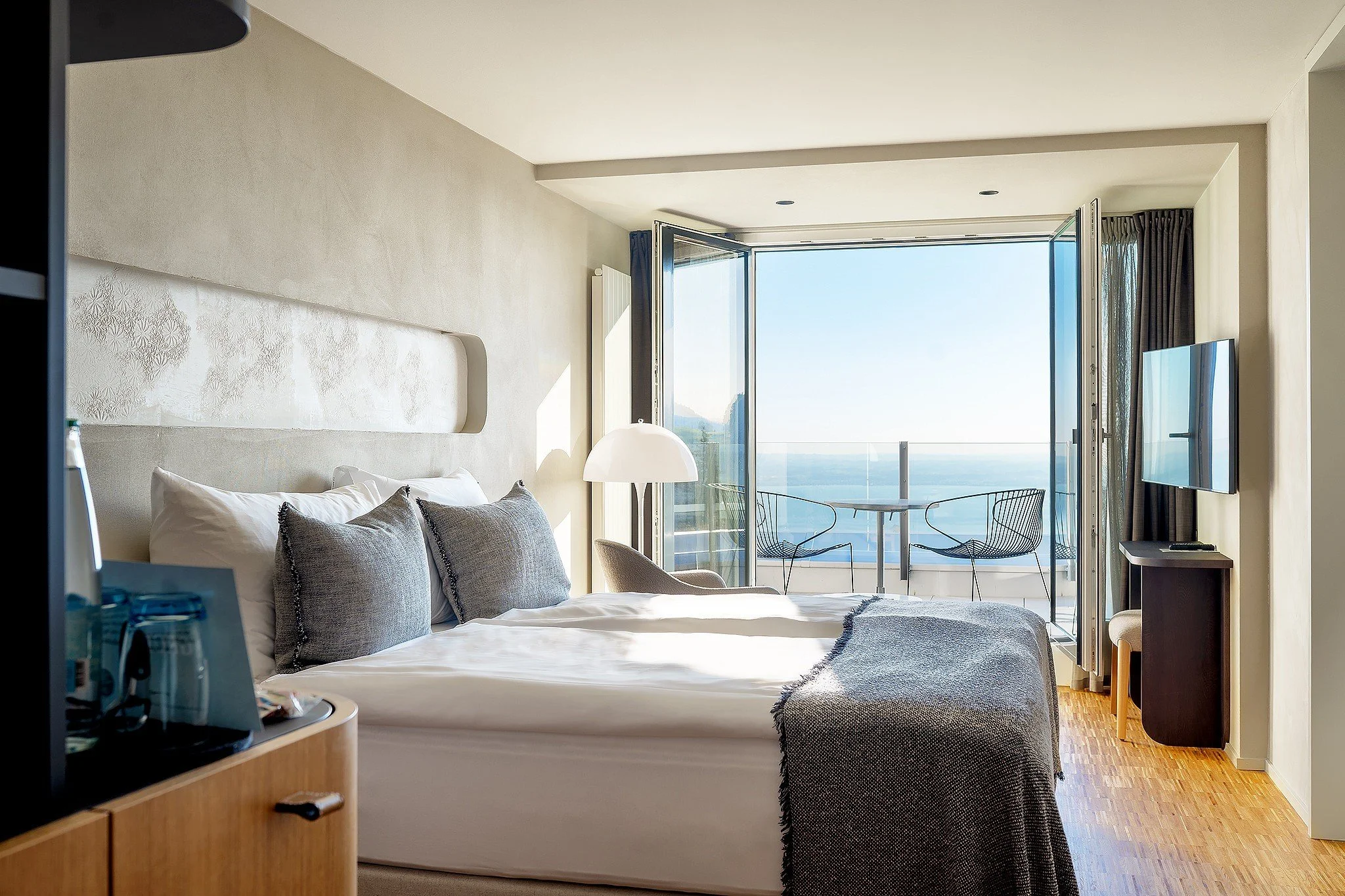 Hotel Heiden guest room with neutral bedding, timber flooring and a balcony overlooking Lake Constance.