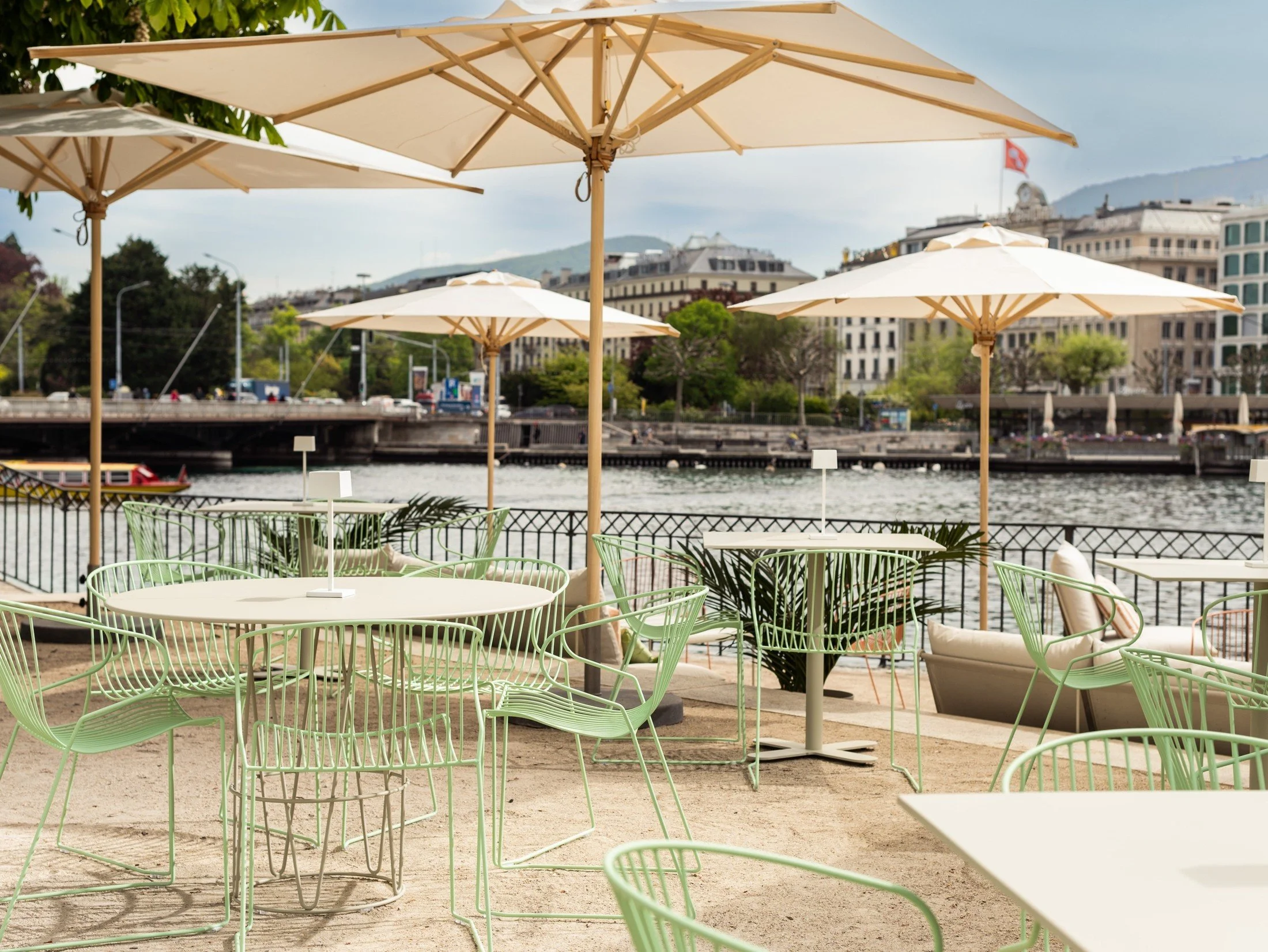 Summer pop-up dining terrace with woven chairs, round tables and broad parasols.