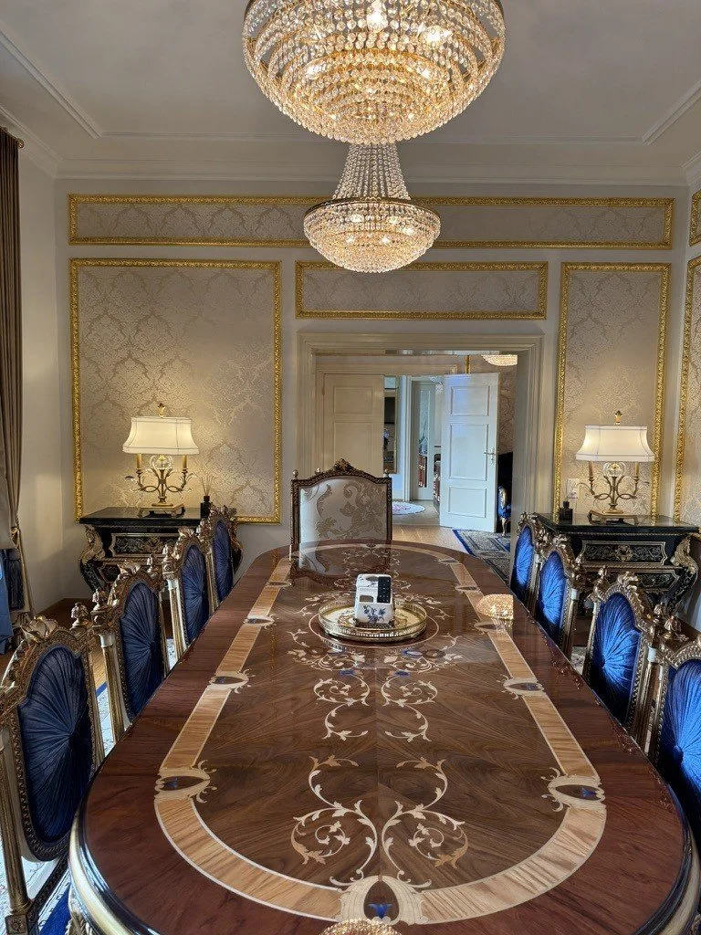 Long conference table with blue and gold chairs beneath a crystal chandelier.