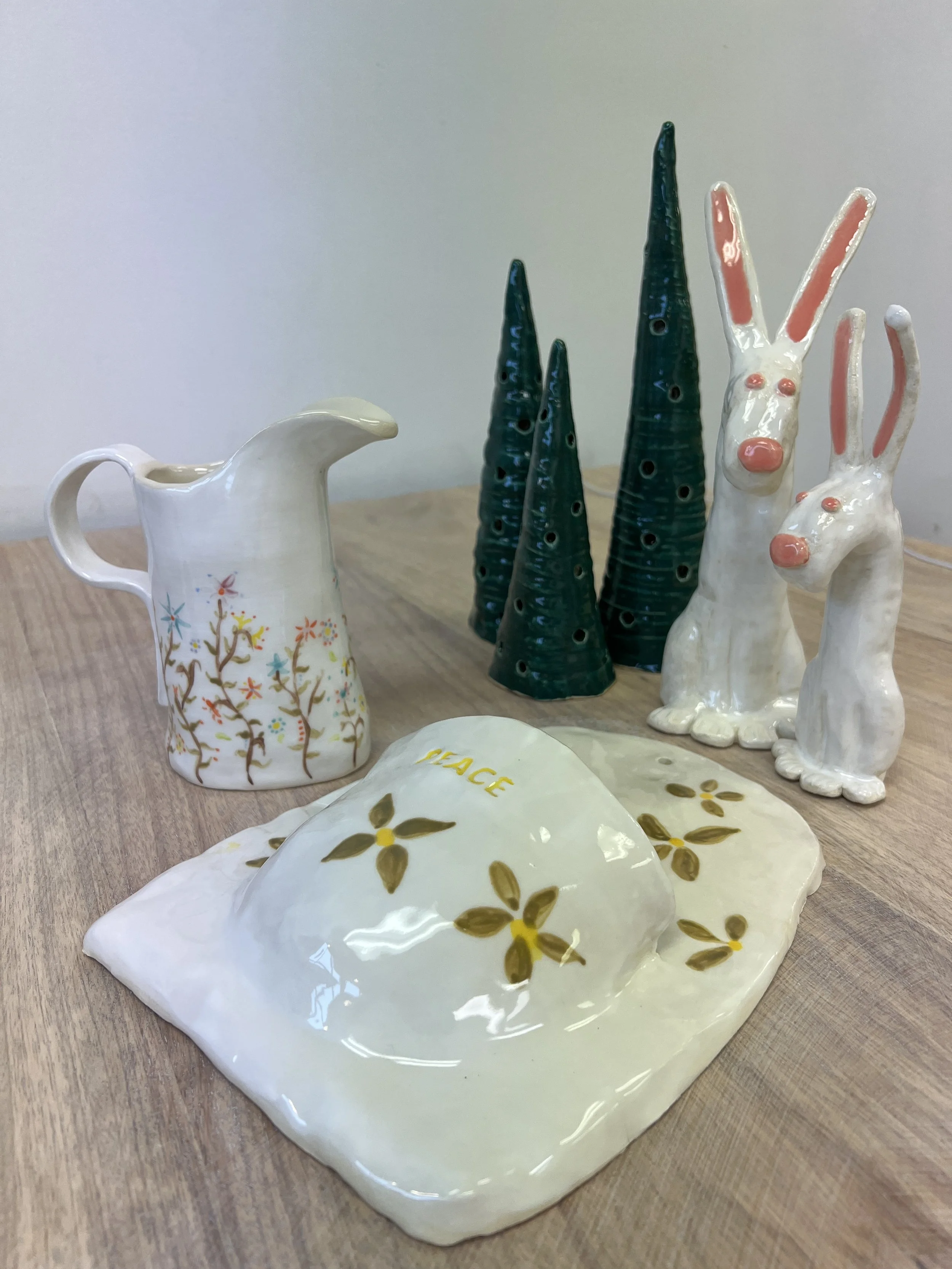 Ceramic pitcher, trees, and rabbit figurines on a wooden table