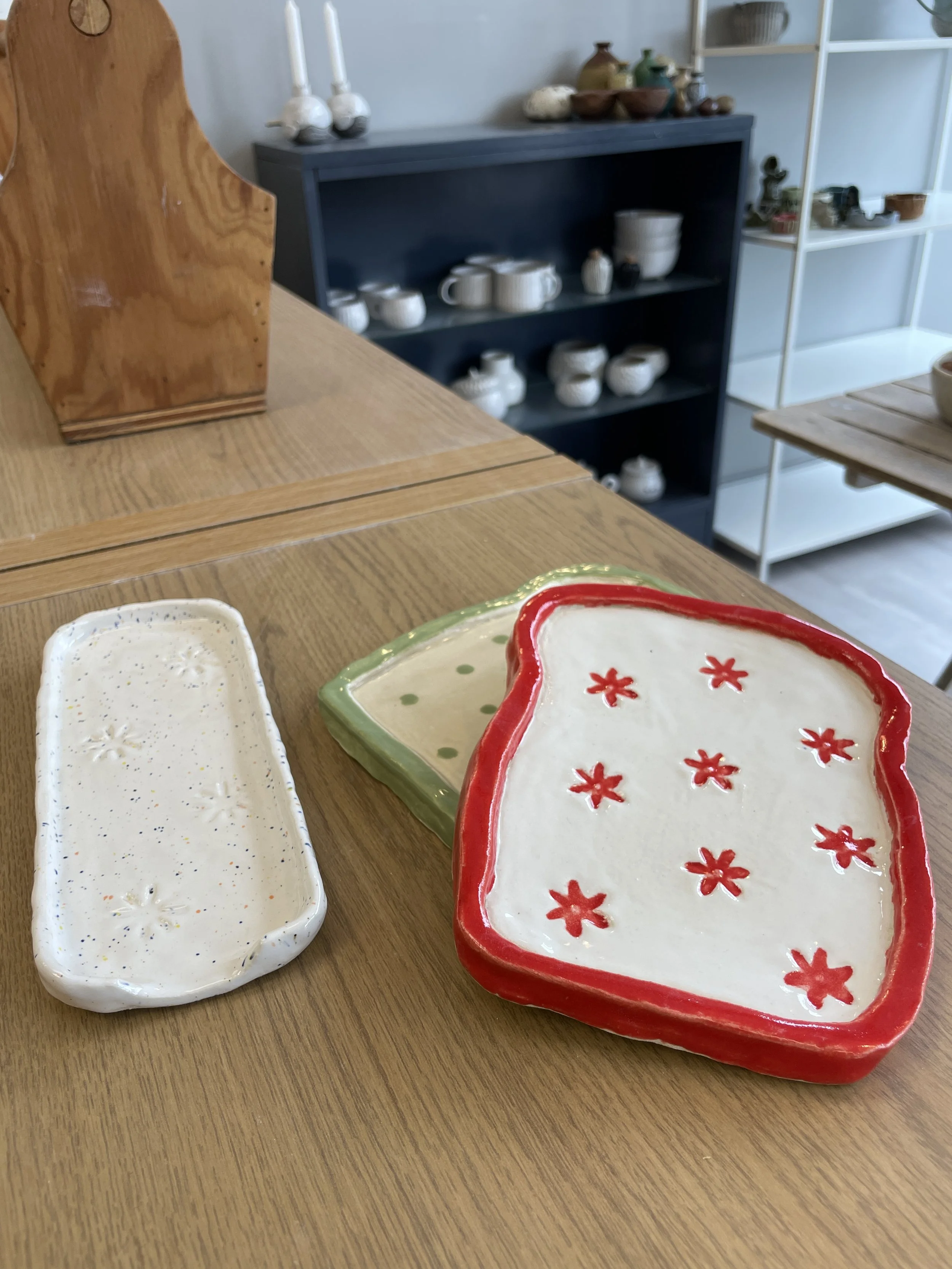Ceramic trays on a wooden table with shelving in the background.