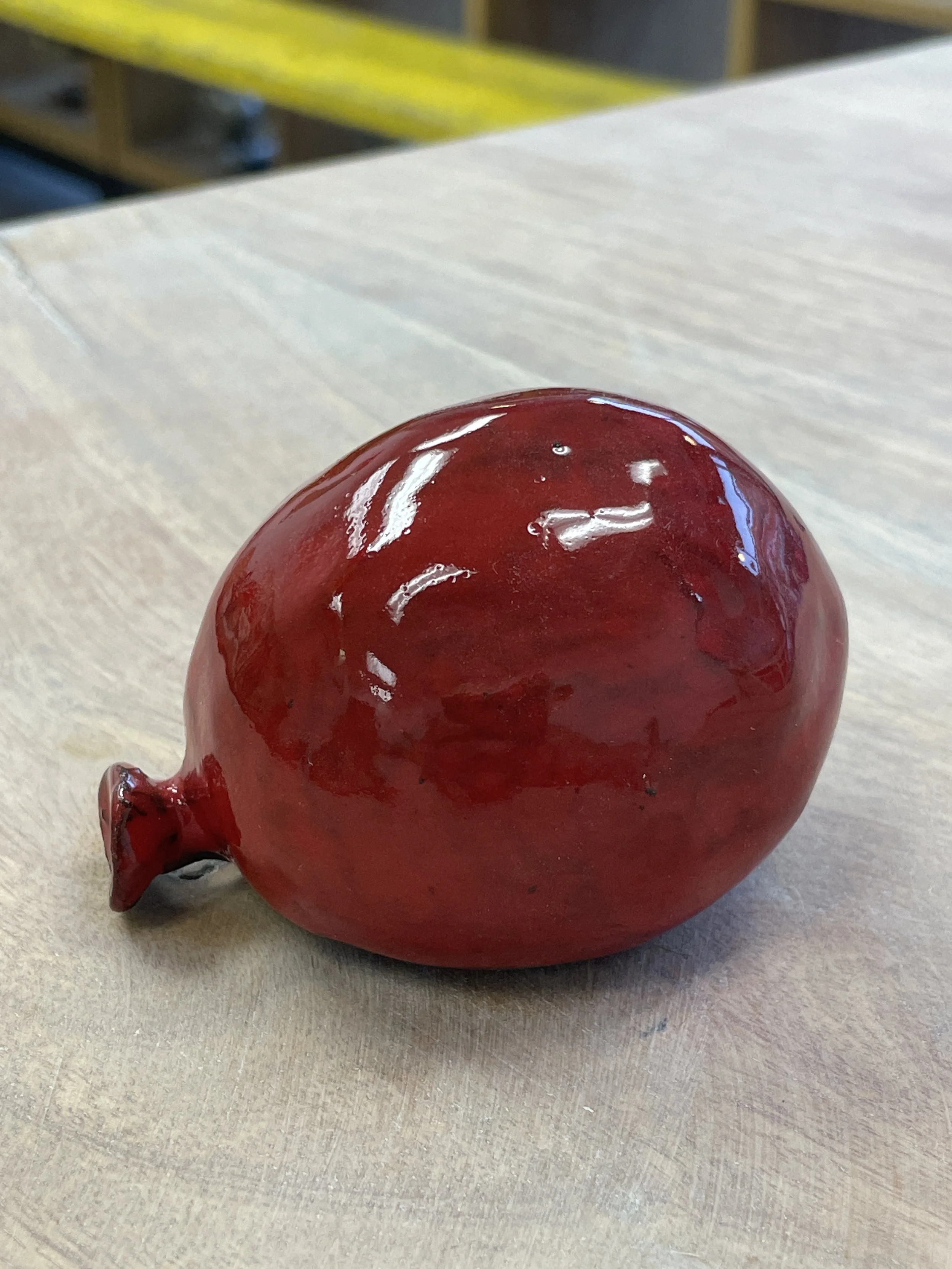 Red ceramic sculpture resembling a water balloon on a wooden surface.