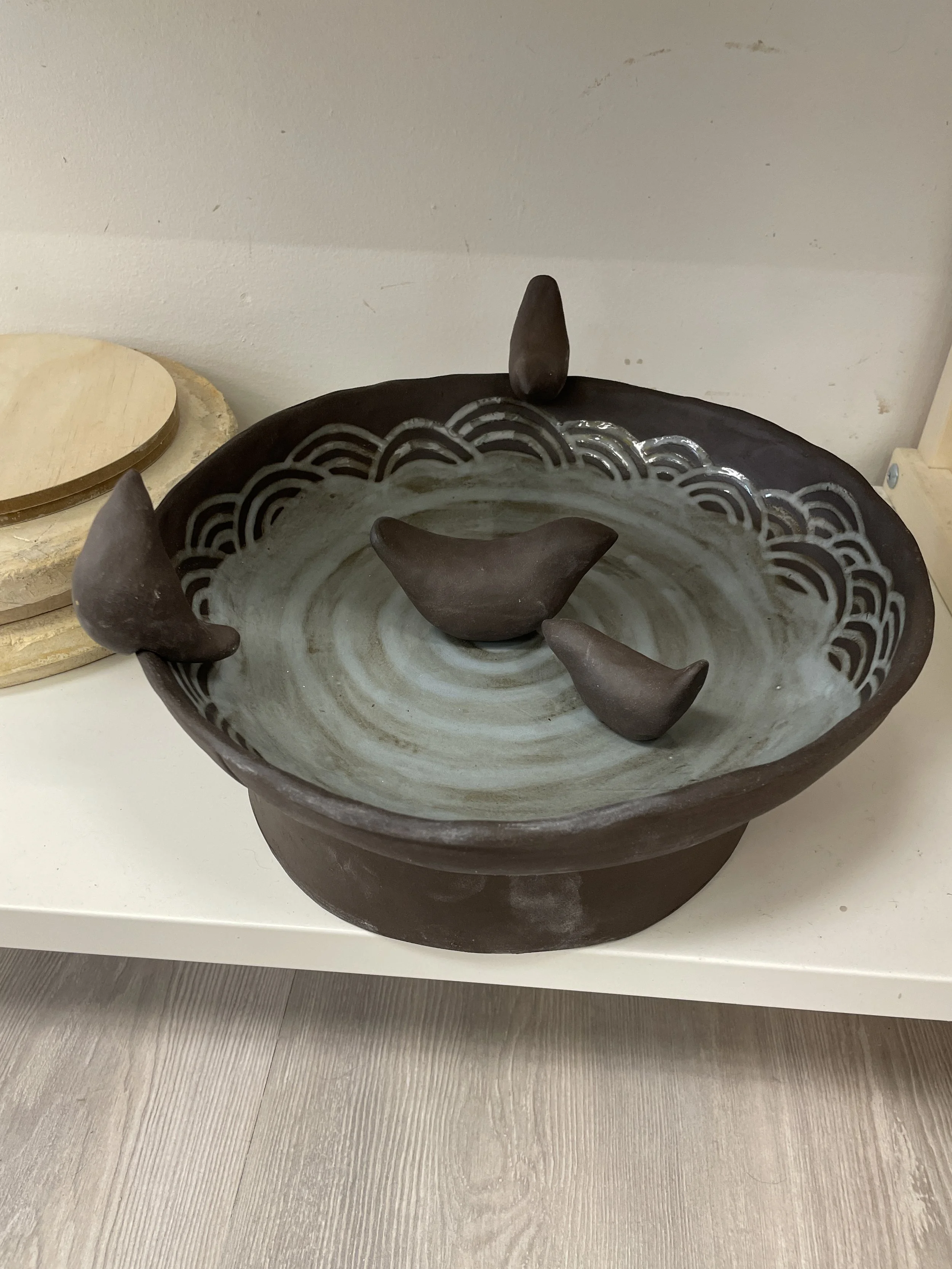 Ceramic bird bath with bird sculptures on rim