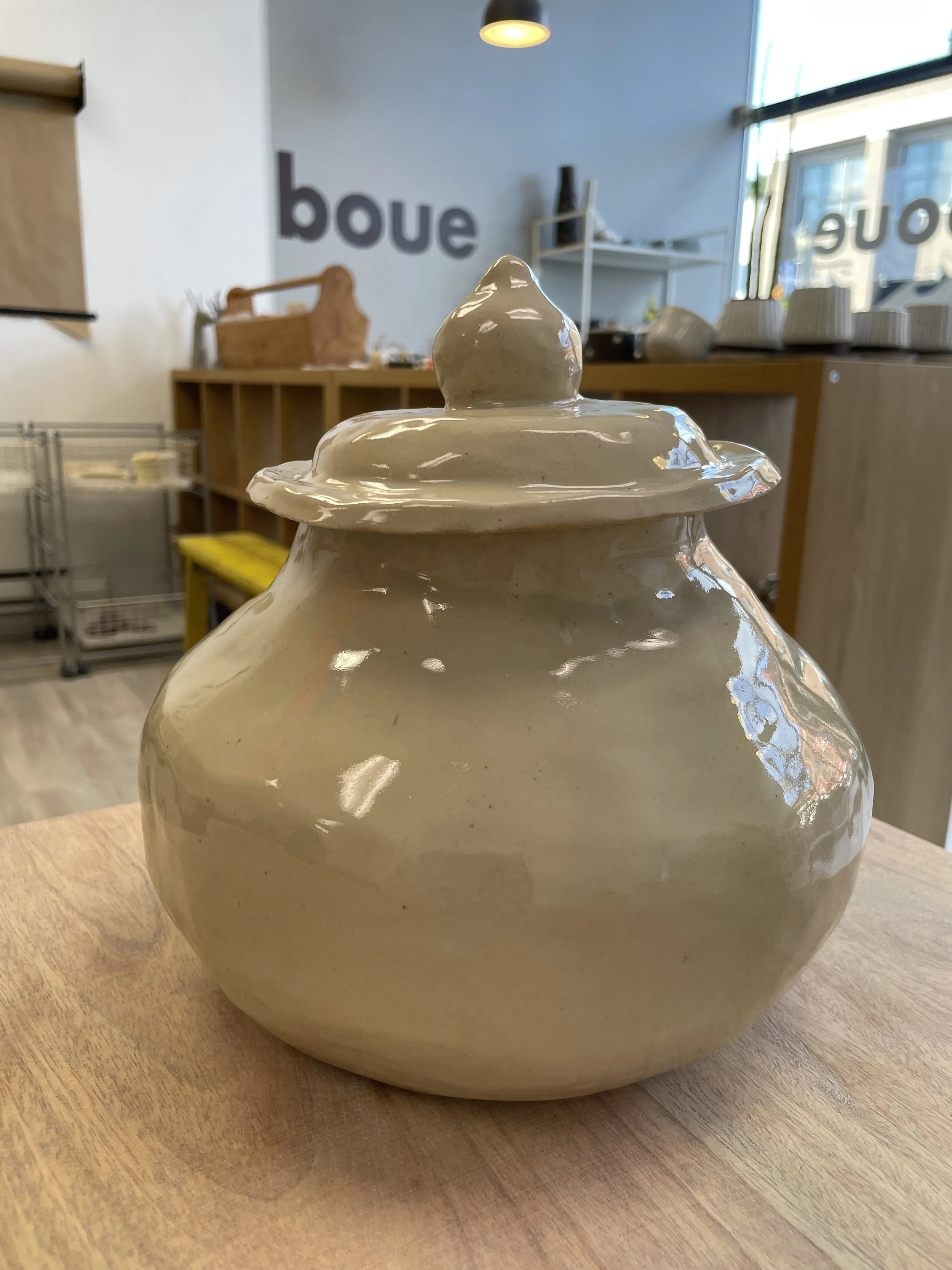 Ceramic jar with lid on wooden table in modern studio setting