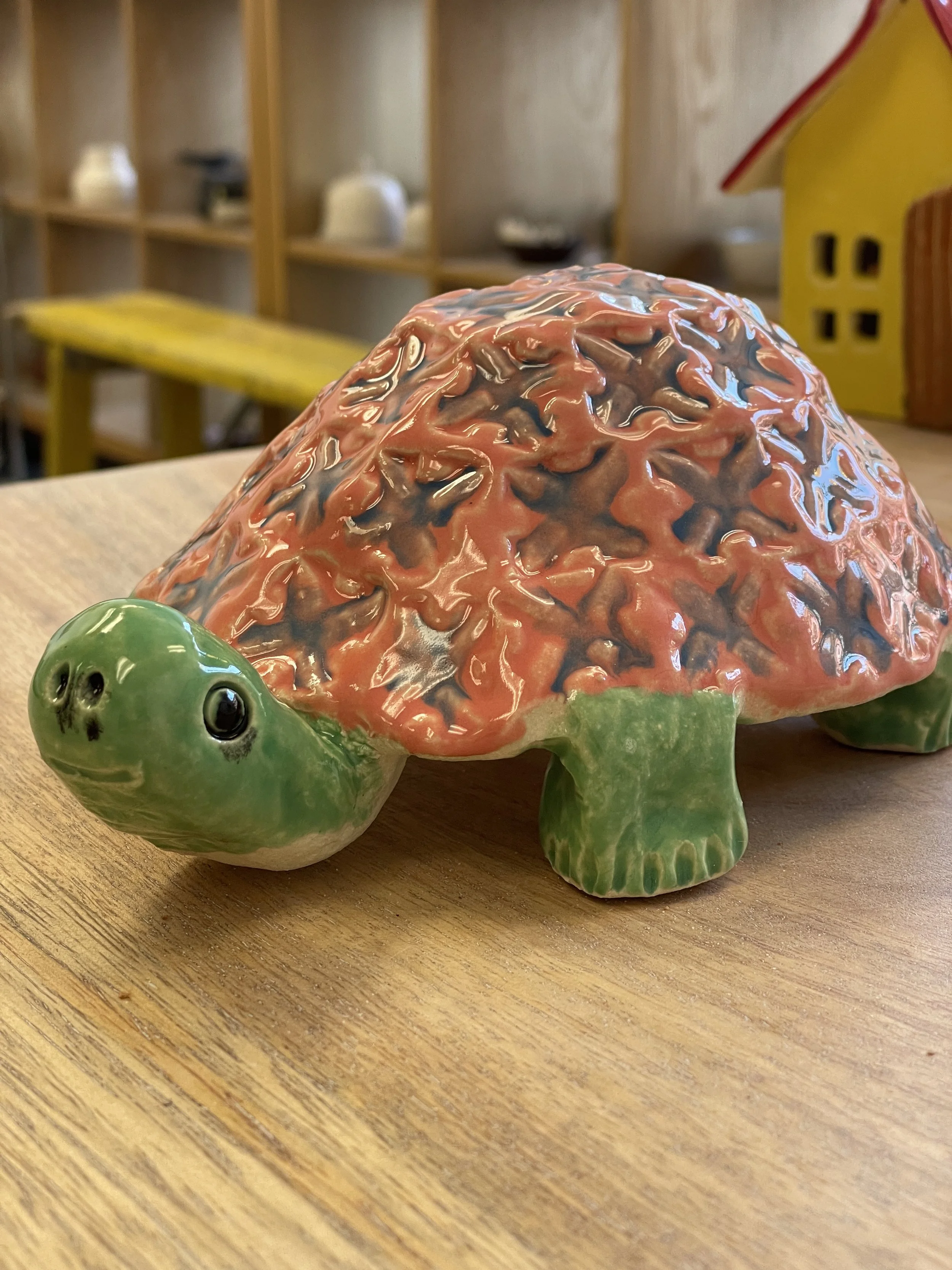 Ceramic turtle figurine with textured, multicolored shell on a wooden surface.