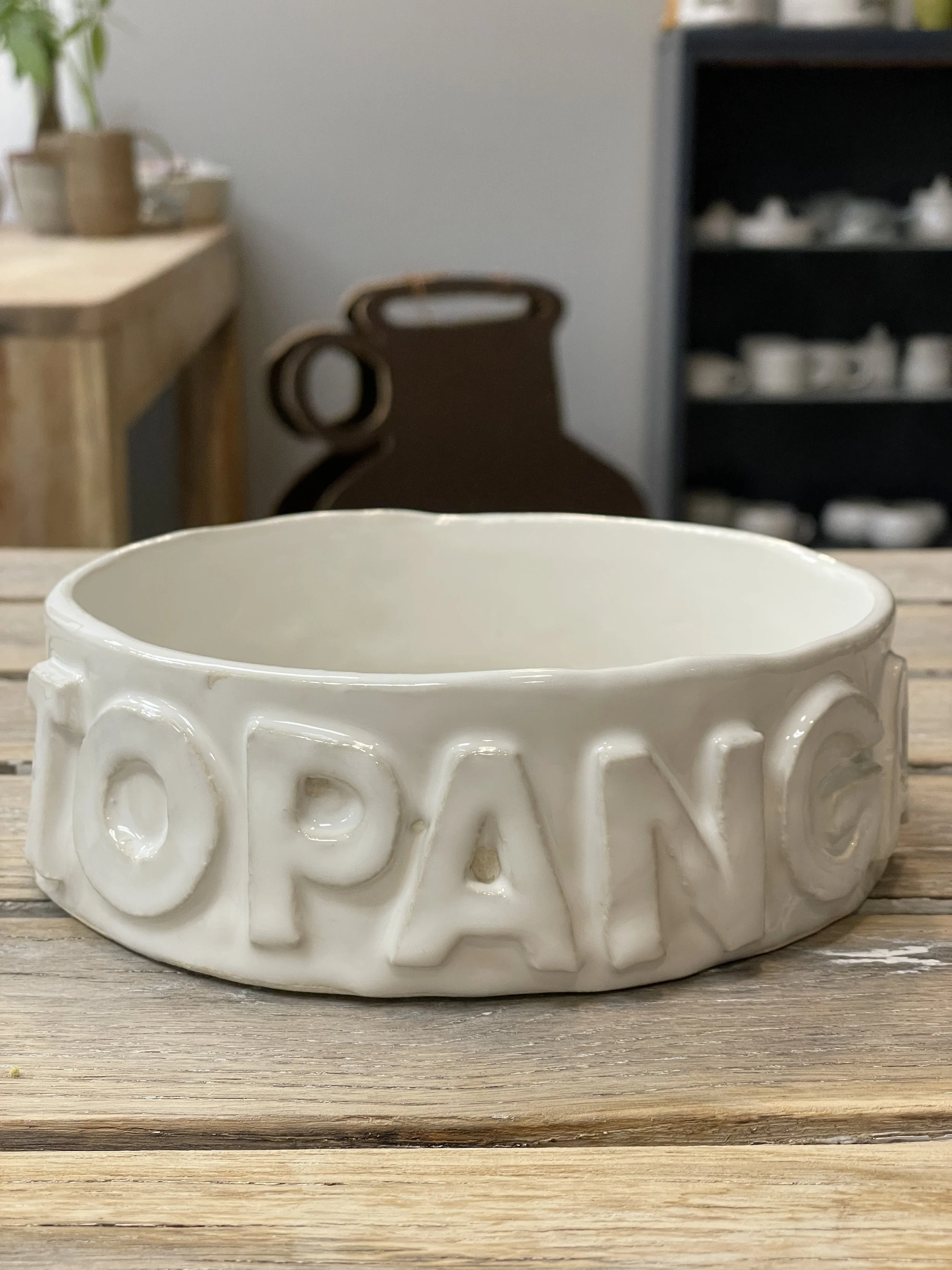 White ceramic bowl with the word 'TOPANGA' embossed on the side, placed on a wooden table.
